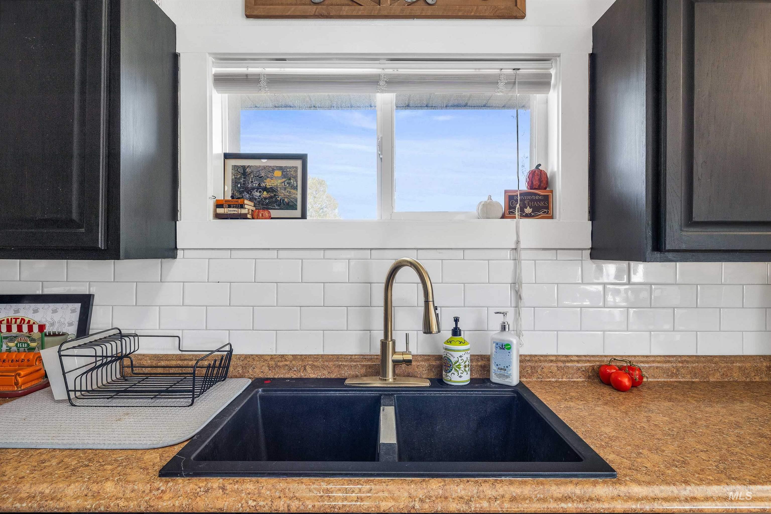 Kitchen featuring decorative backsplash, dark cabinets, and dark countertops