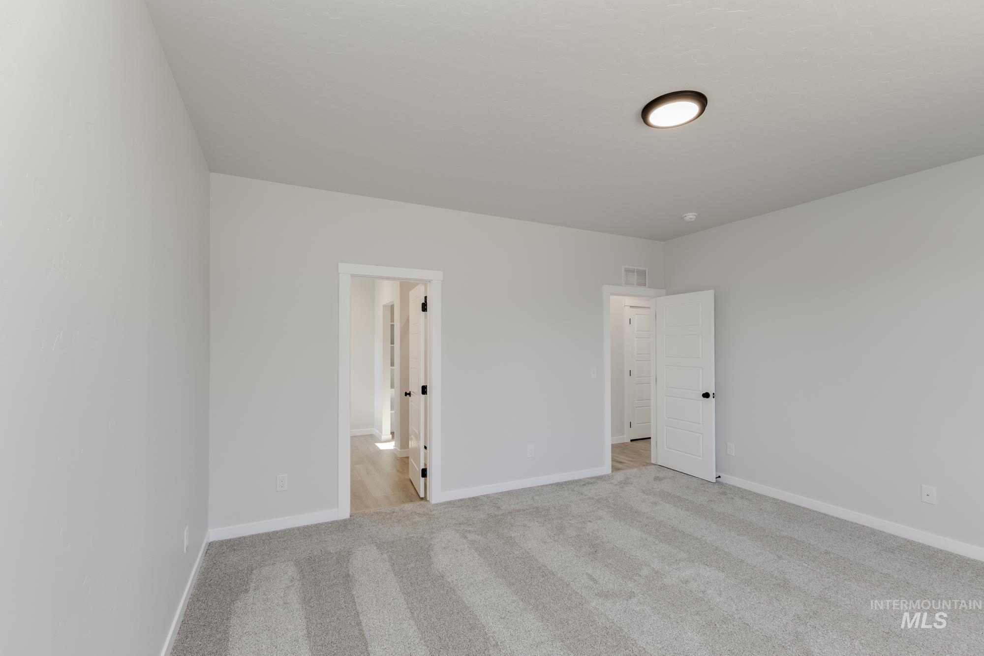Unfurnished bedroom with light colored carpet and baseboards