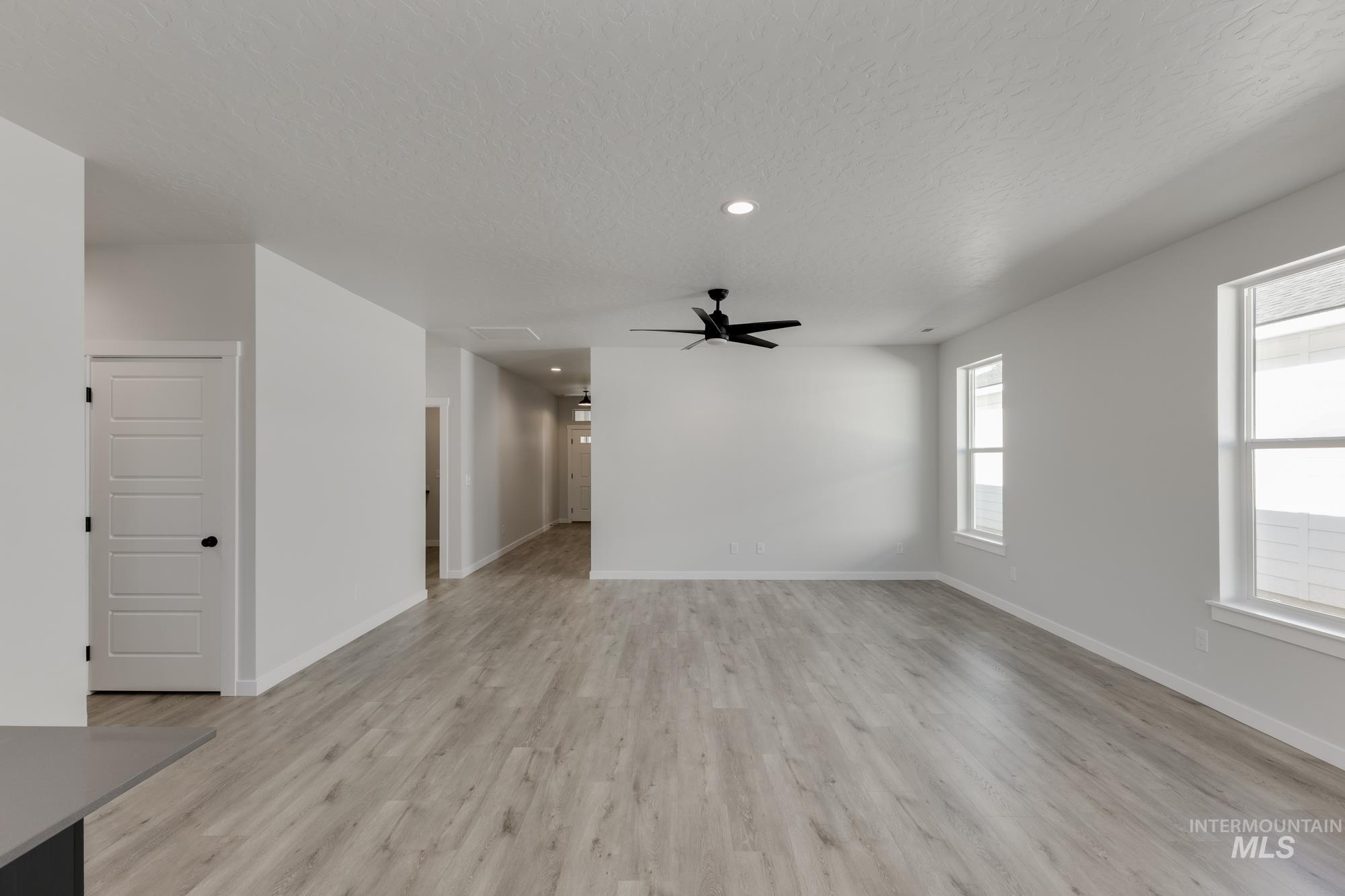 Unfurnished living room featuring recessed lighting, a textured ceiling, light wood-style floors, and a ceiling fan