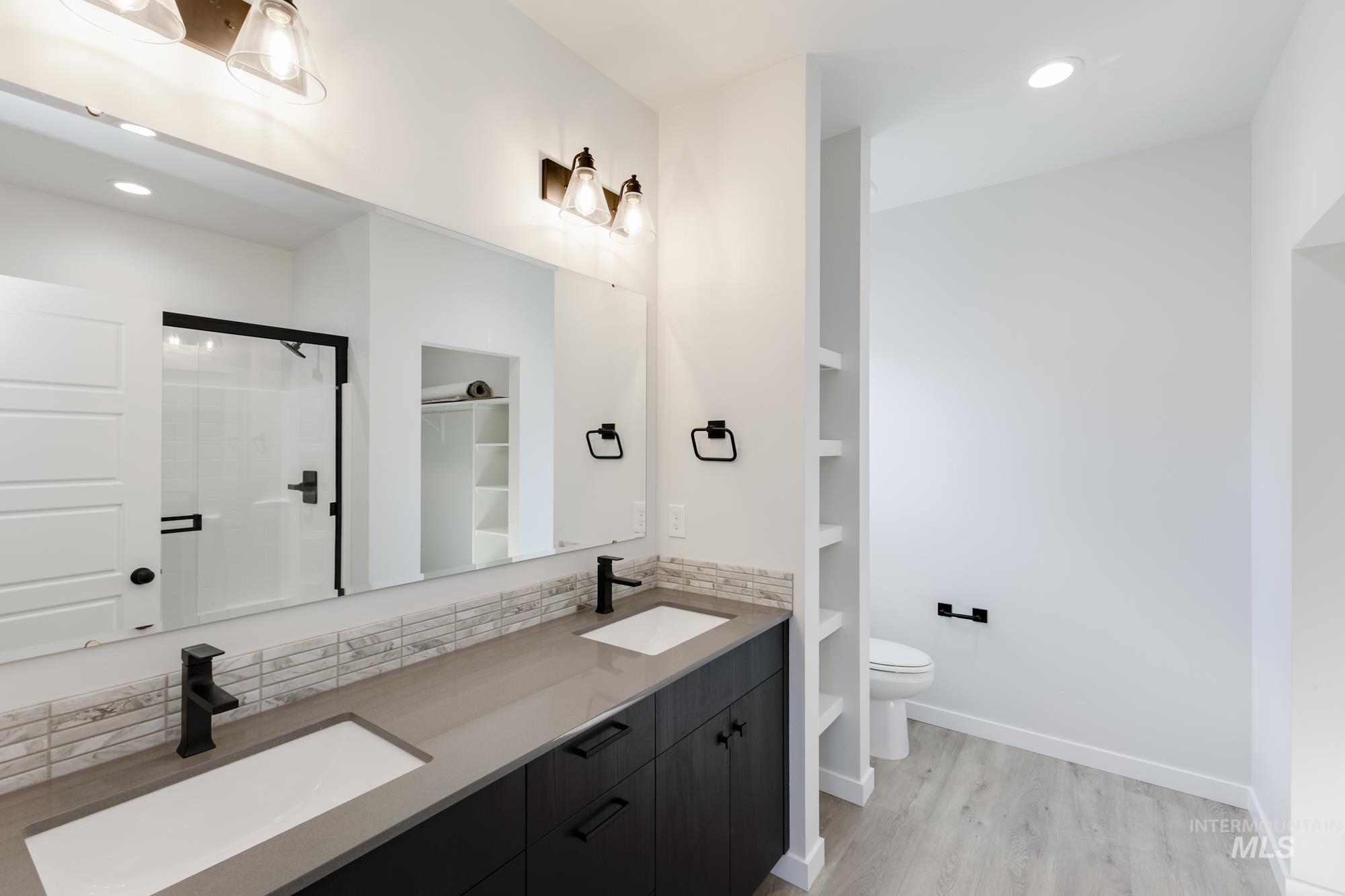 Full bathroom with recessed lighting, a shower stall, backsplash, light wood-style floors, and double vanity