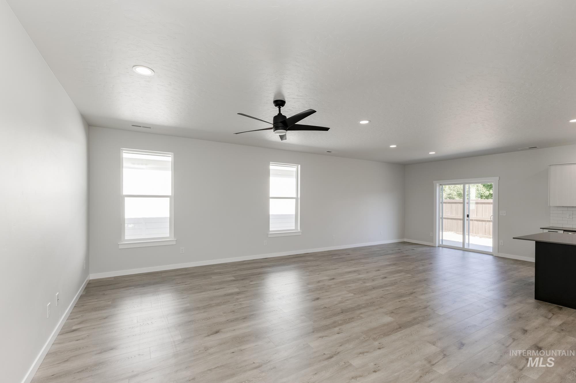 Unfurnished living room featuring a ceiling fan, light wood-type flooring, and recessed lighting