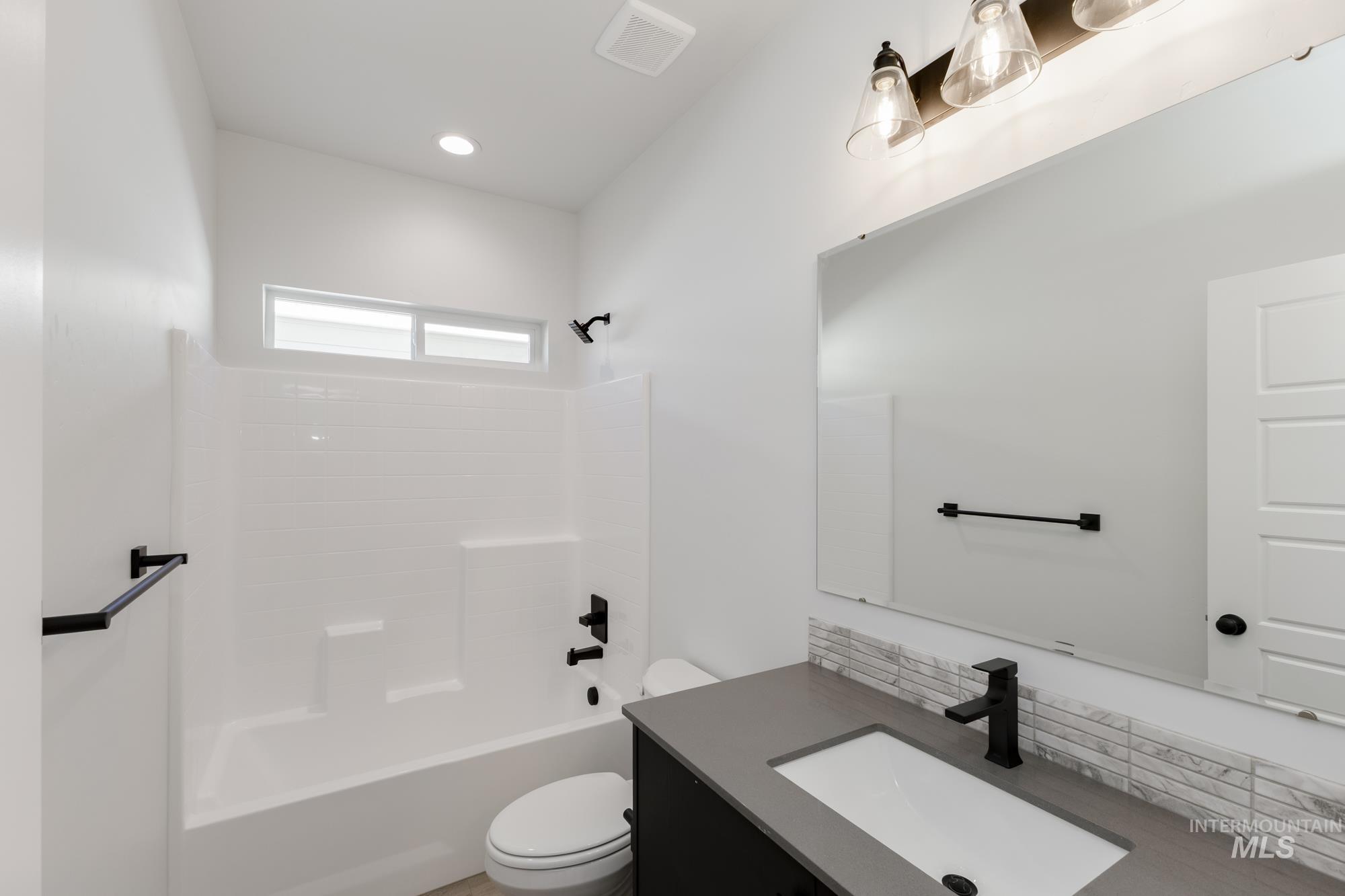 Bathroom featuring decorative backsplash, vanity, shower / washtub combination, and recessed lighting