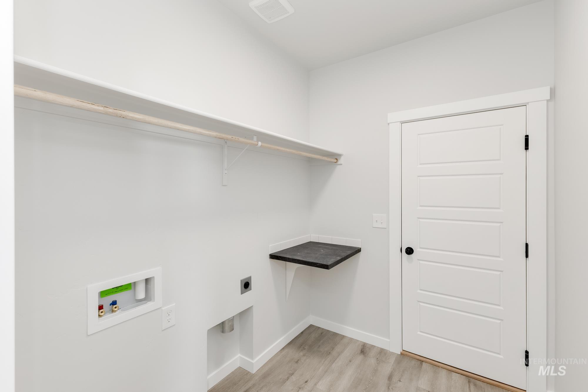 Laundry area featuring light wood finished floors, washer hookup, and electric dryer hookup