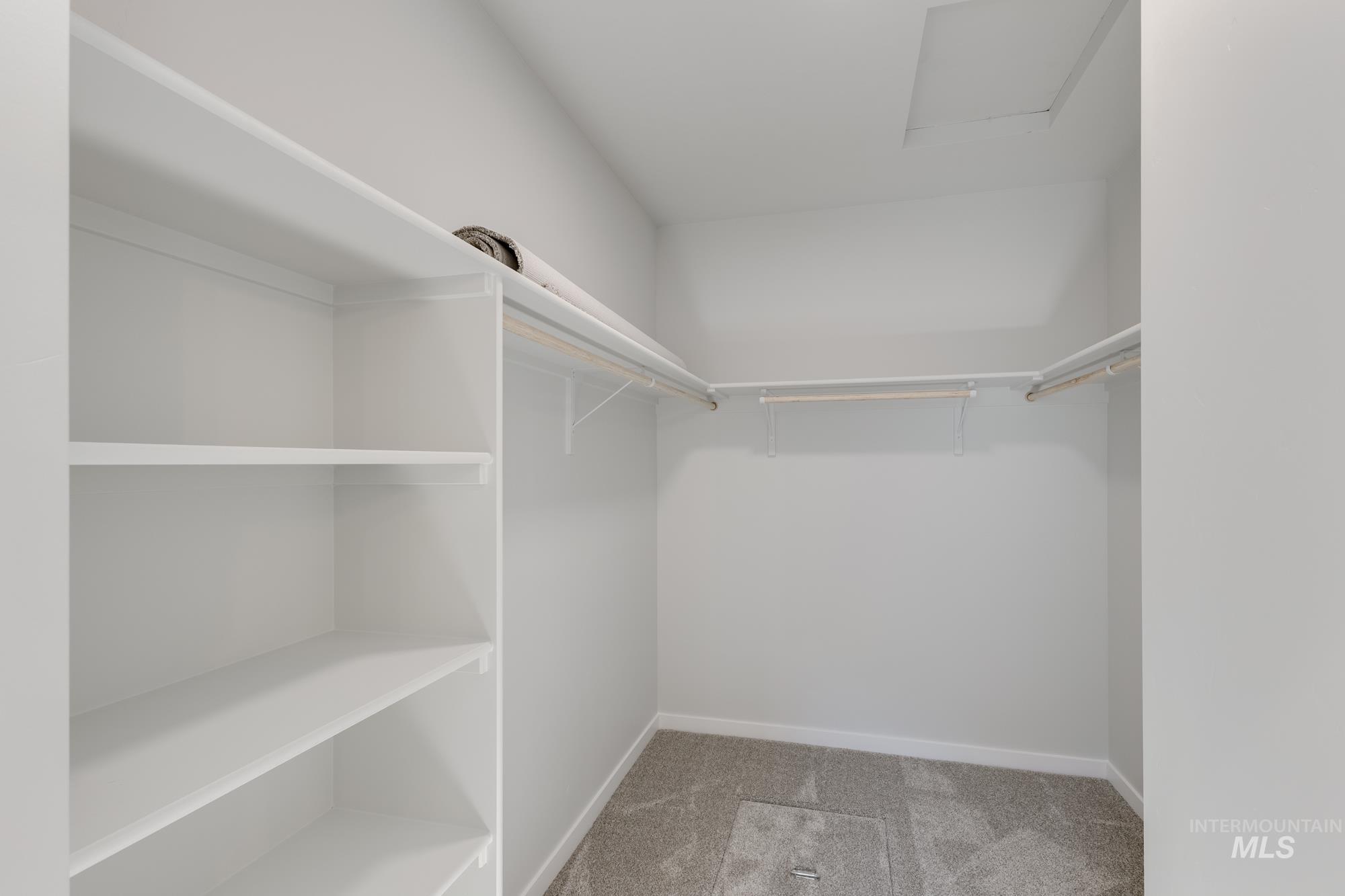 Walk in closet with light colored carpet and attic access