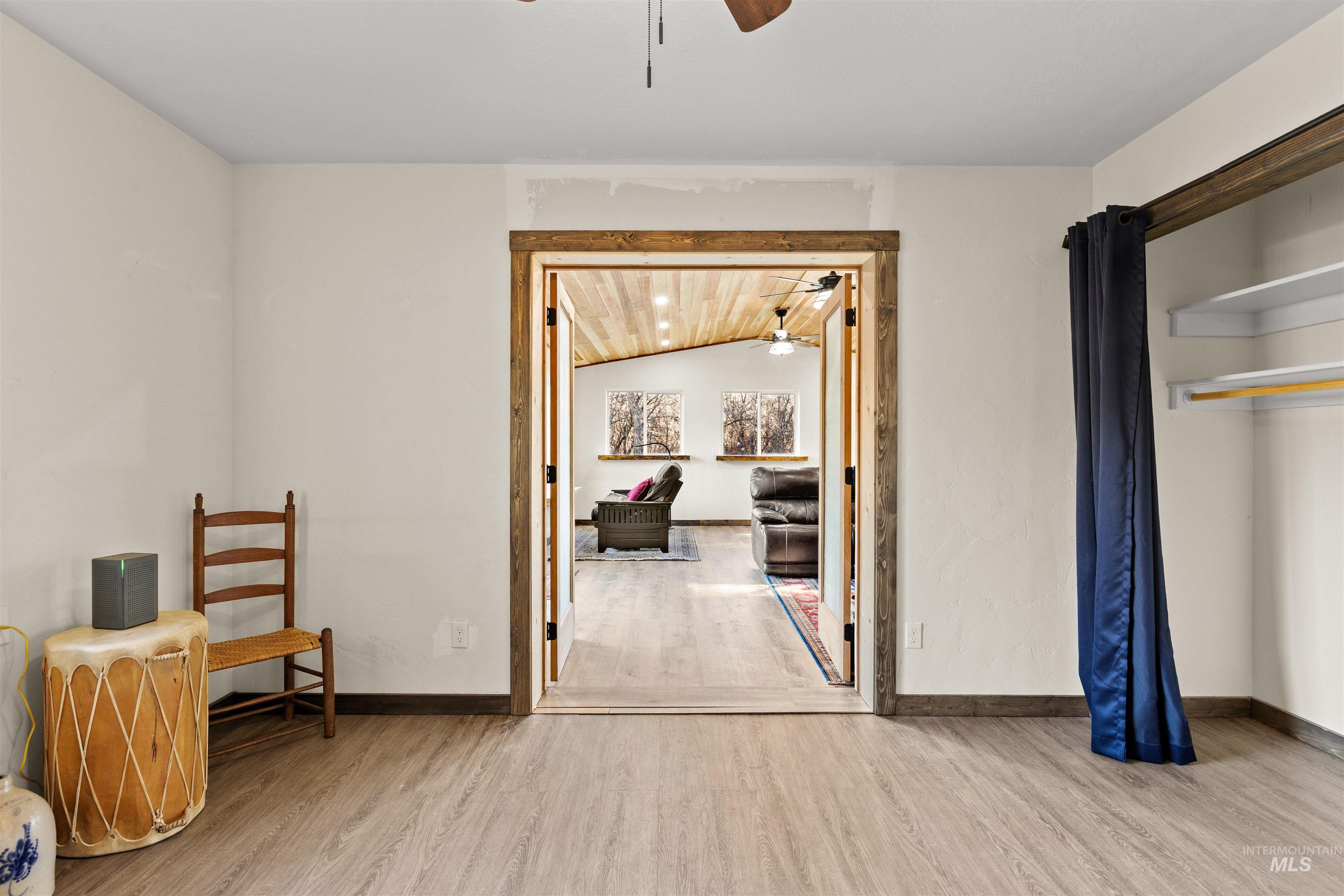 Sitting room with lofted ceiling, light wood-style floors, and a ceiling fan