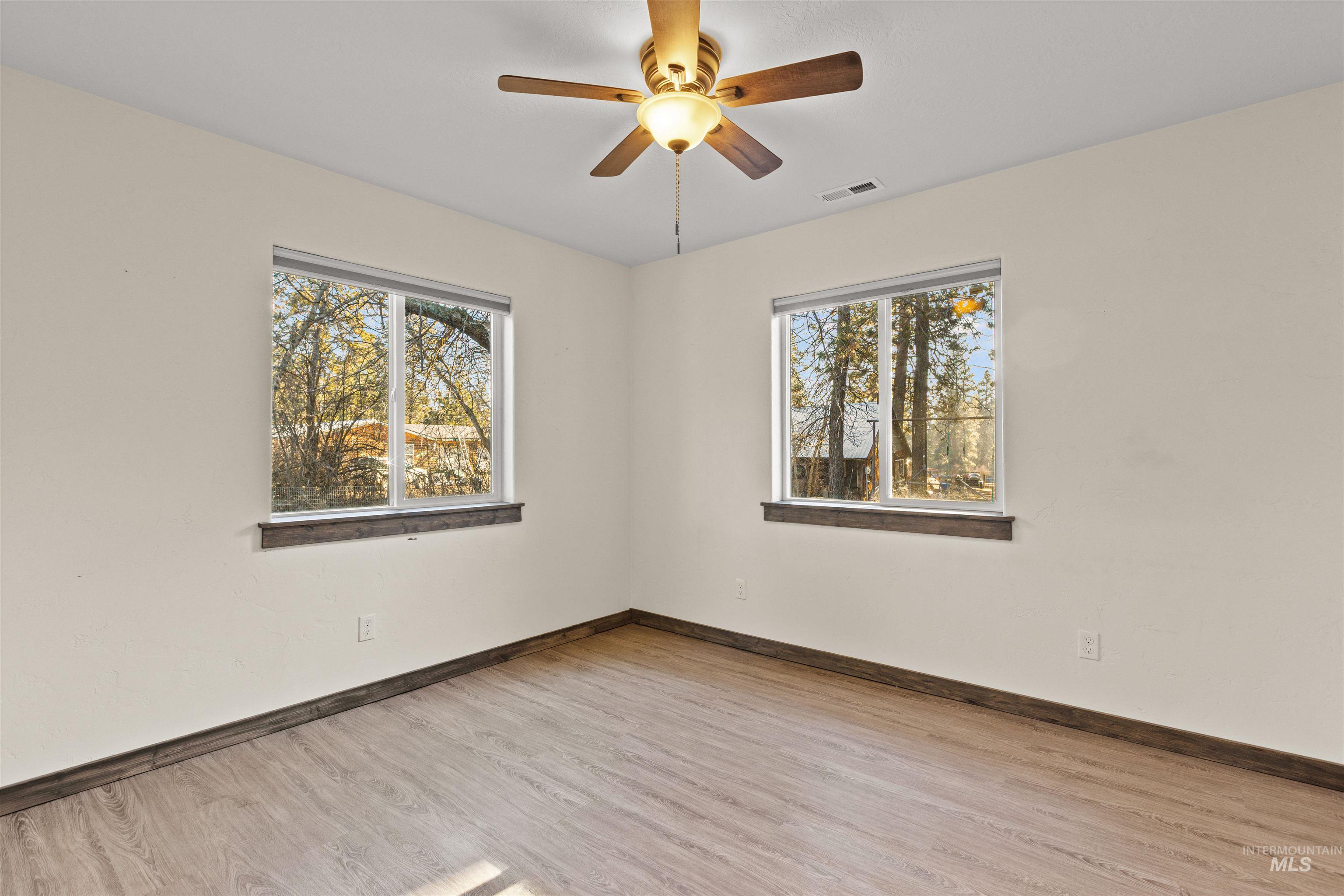 Empty room with healthy amount of natural light, light wood finished floors, and a ceiling fan