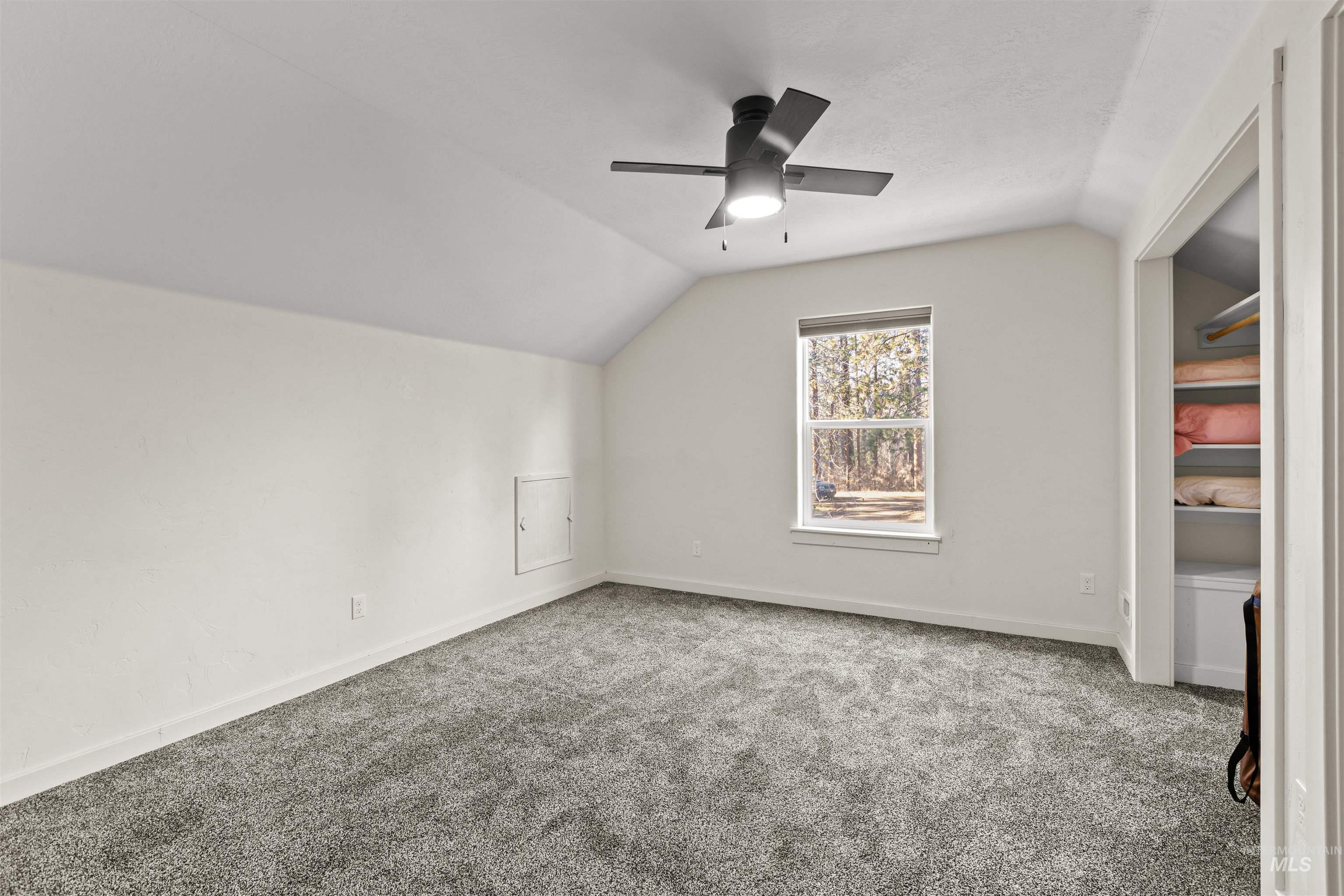 Additional living space with vaulted ceiling, carpet floors, and a ceiling fan
