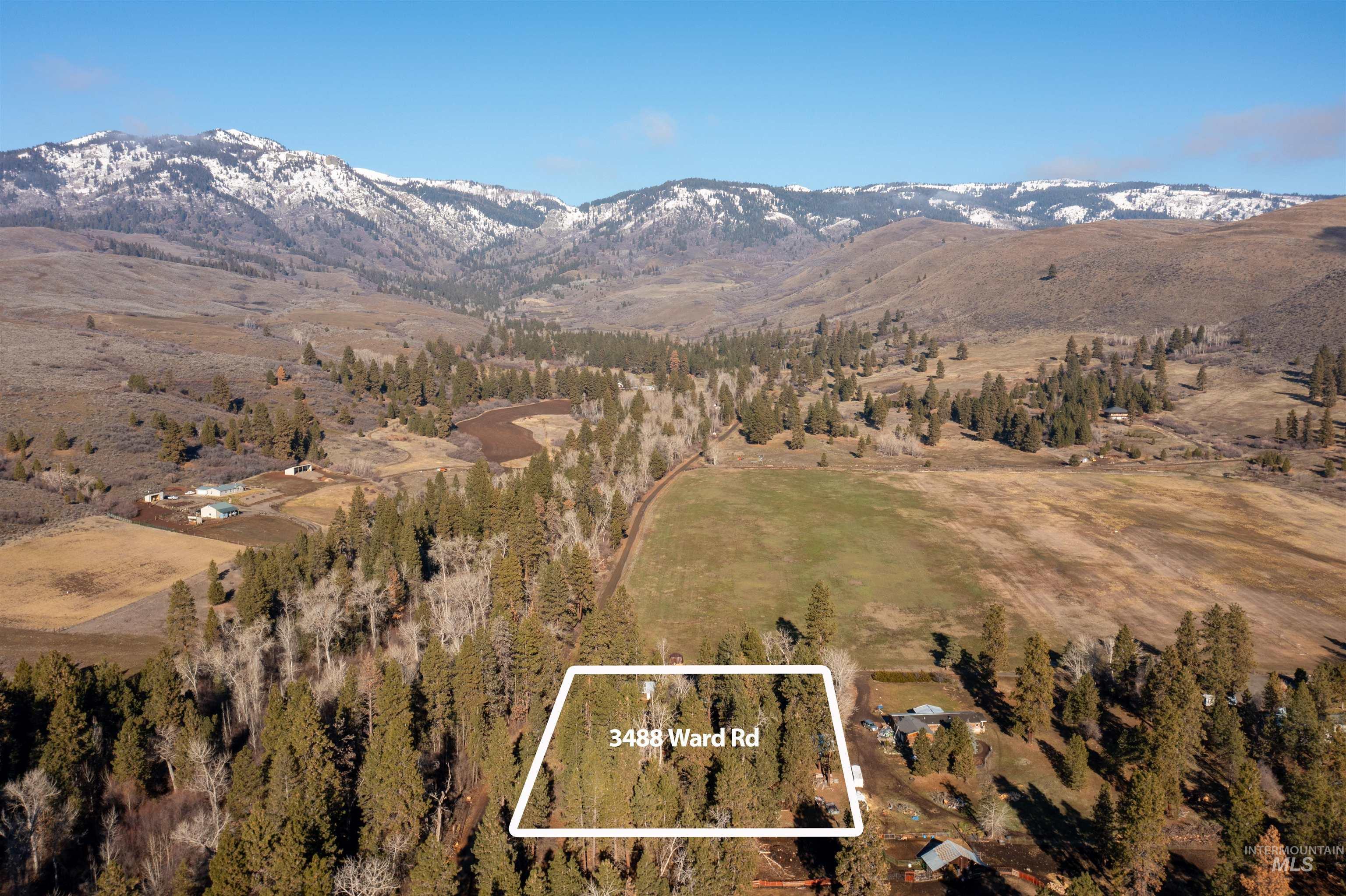 Aerial view of property and surrounding area featuring property boundaries highlighted and a mountain backdrop