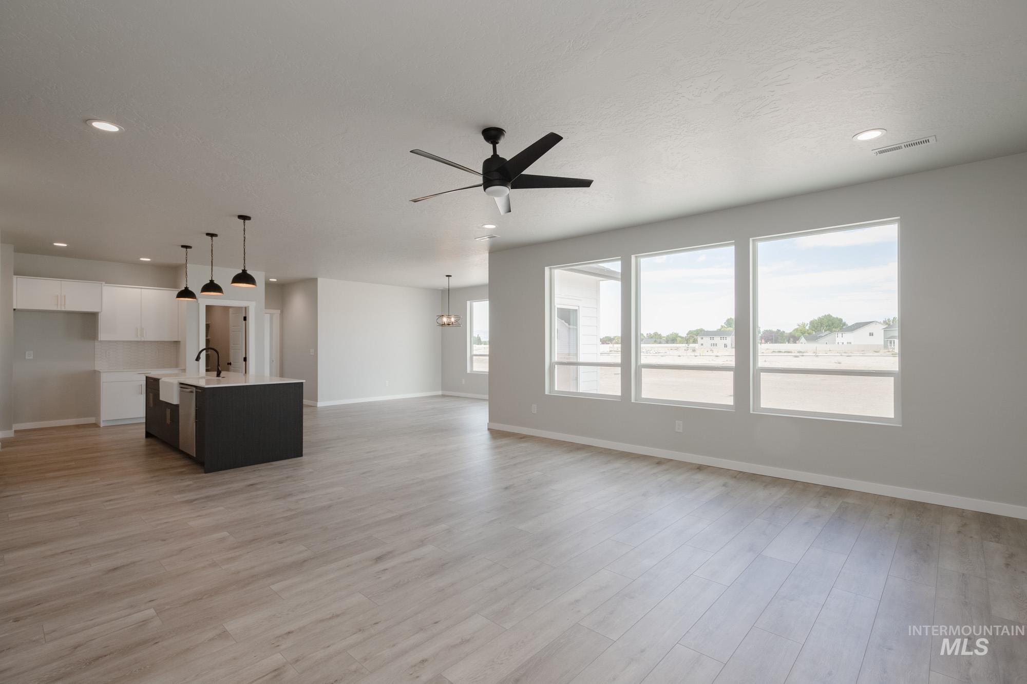 Unfurnished living room with a ceiling fan, light wood-style floors, recessed lighting, and a chandelier