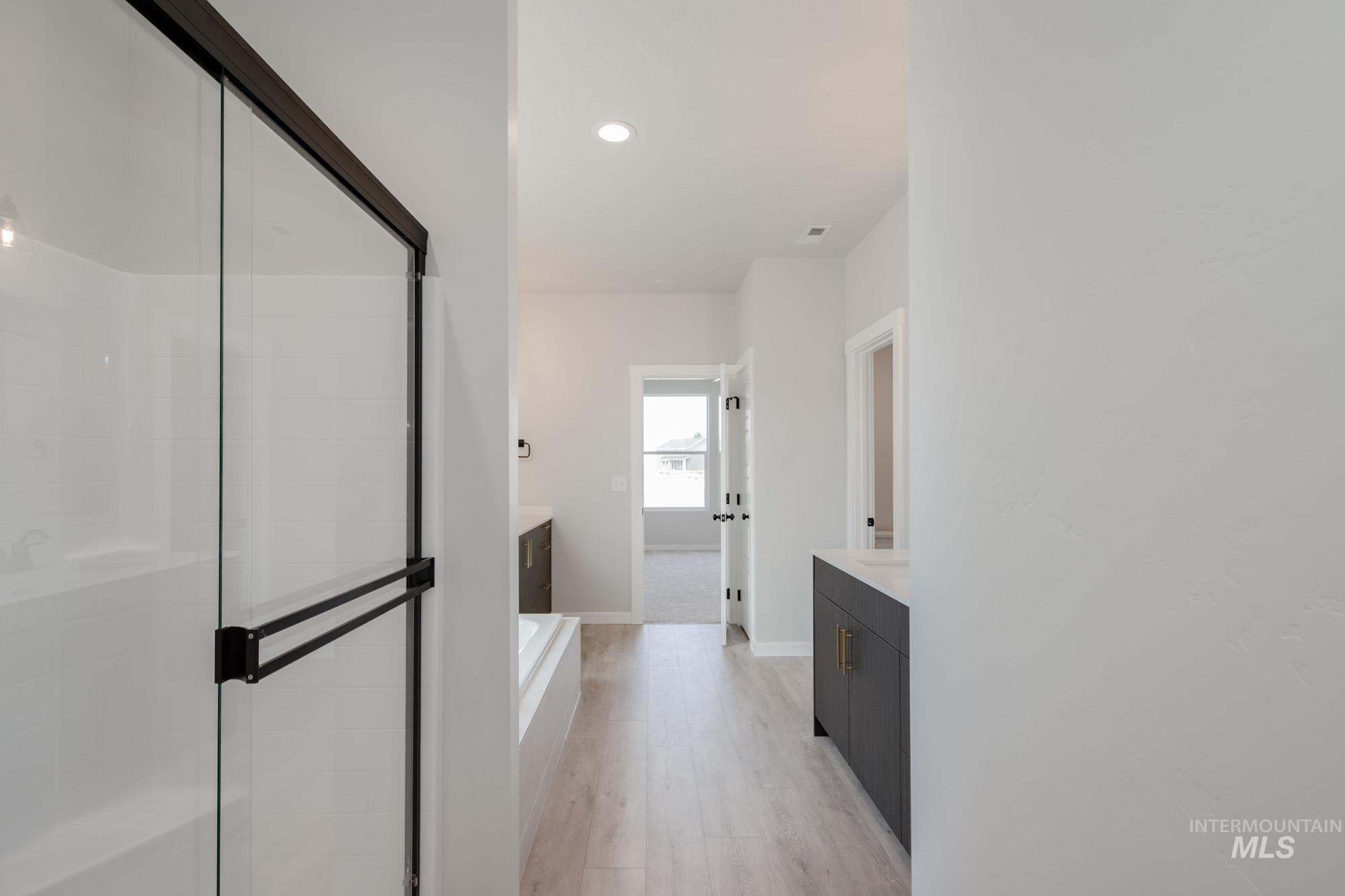 Bathroom featuring vanity, a stall shower, a bath, recessed lighting, and light wood-style flooring