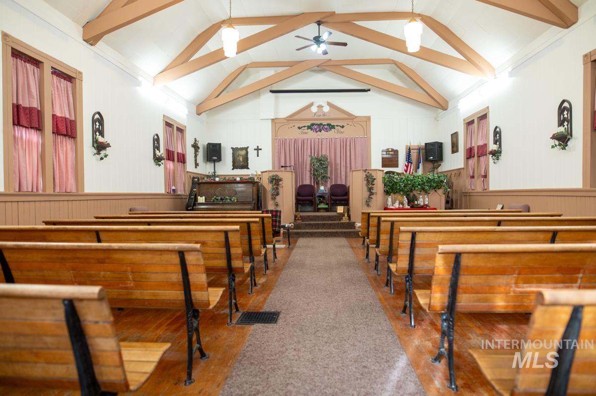 Misc room featuring a ceiling fan, wooden walls, wainscoting, and beam ceiling