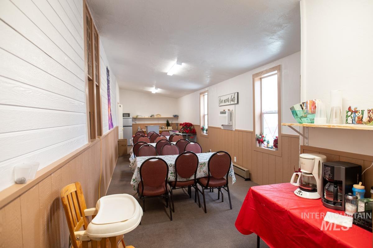 Carpeted dining space featuring wooden walls, wainscoting, and a baseboard radiator