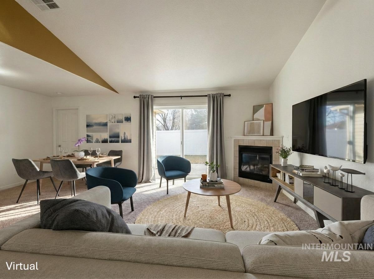 Living area featuring lofted ceiling, a fireplace, and carpet flooring