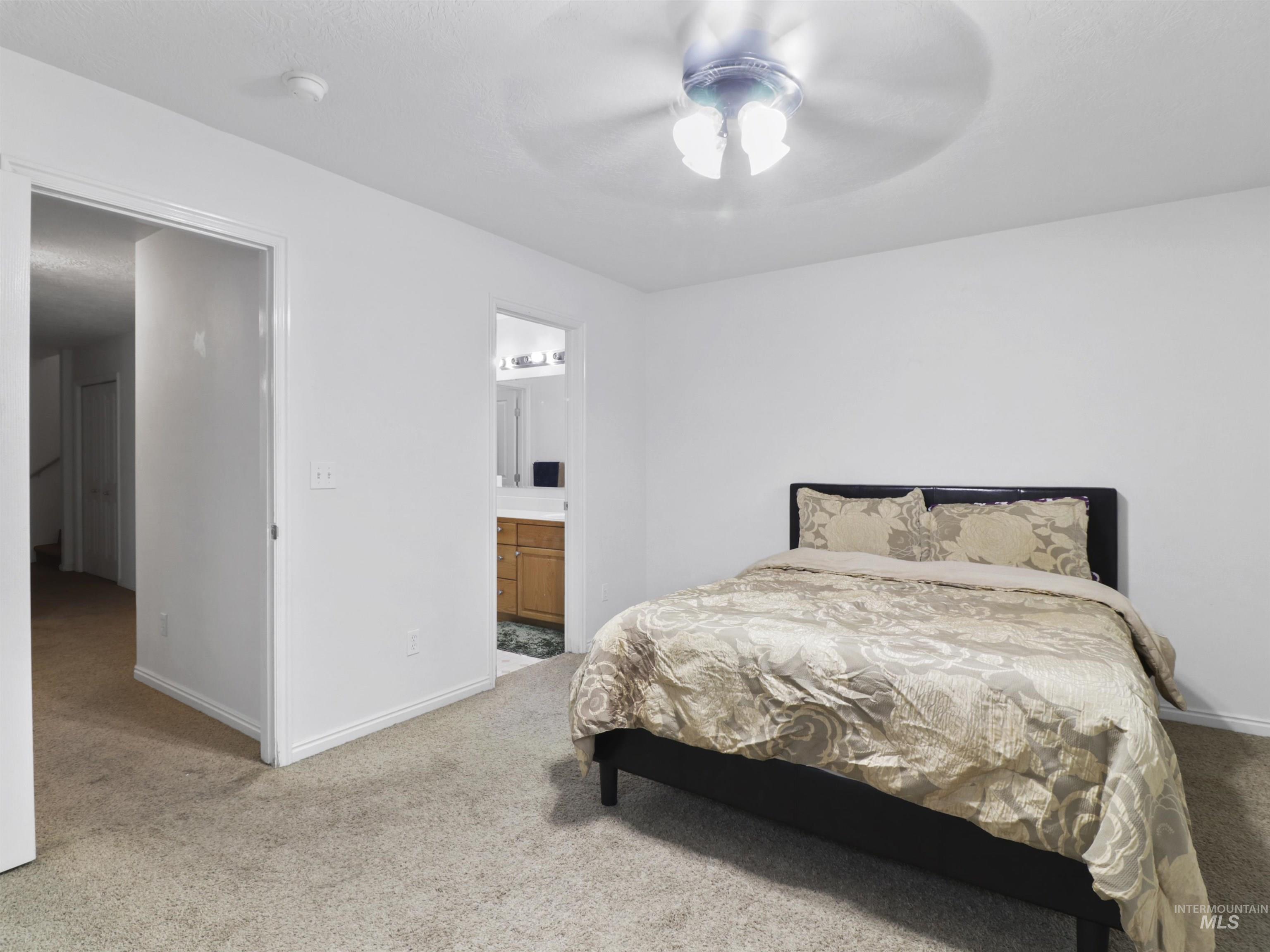 Carpeted bedroom with a ceiling fan and connected bathroom