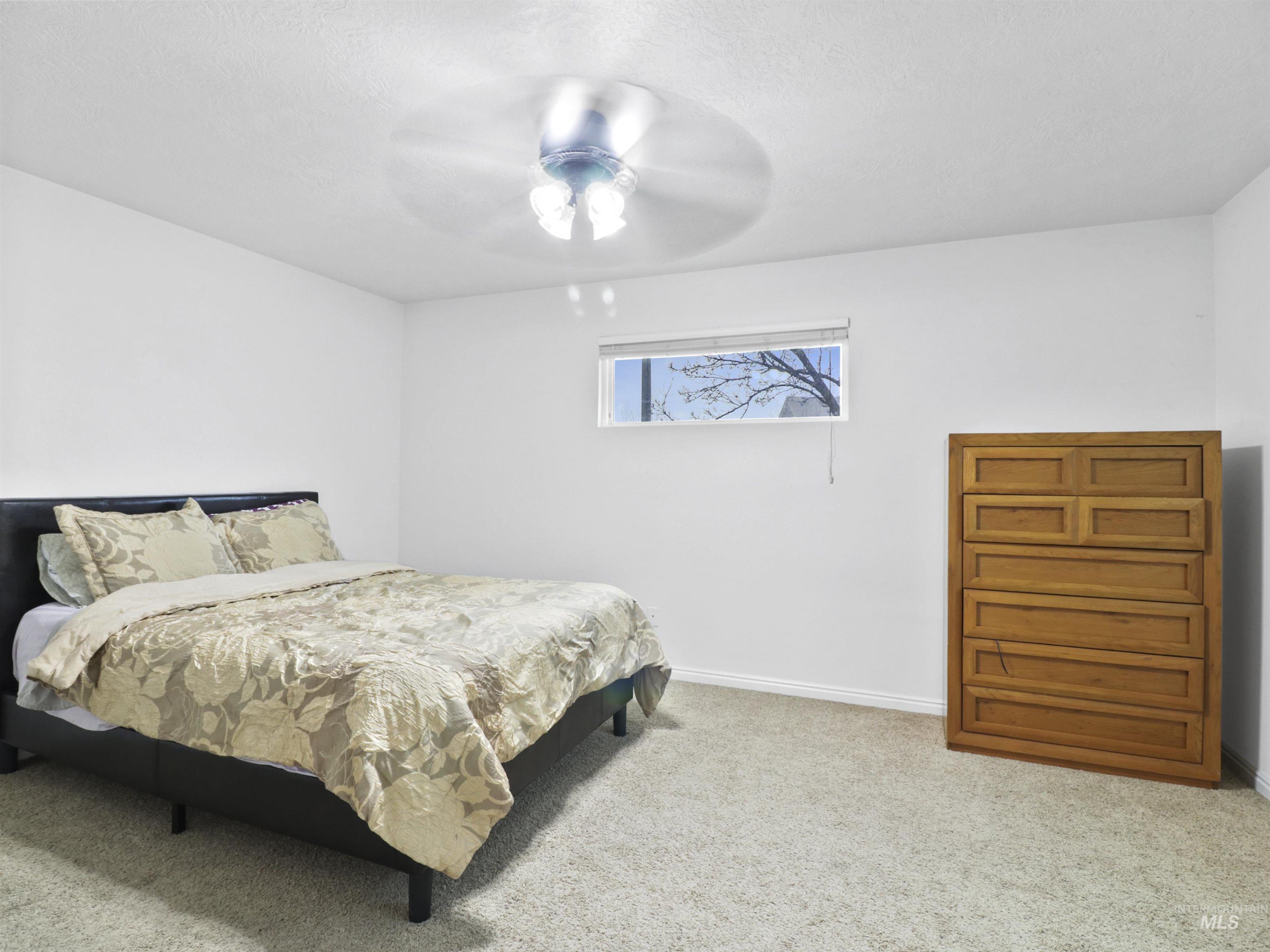 Carpeted bedroom with a ceiling fan and a textured ceiling