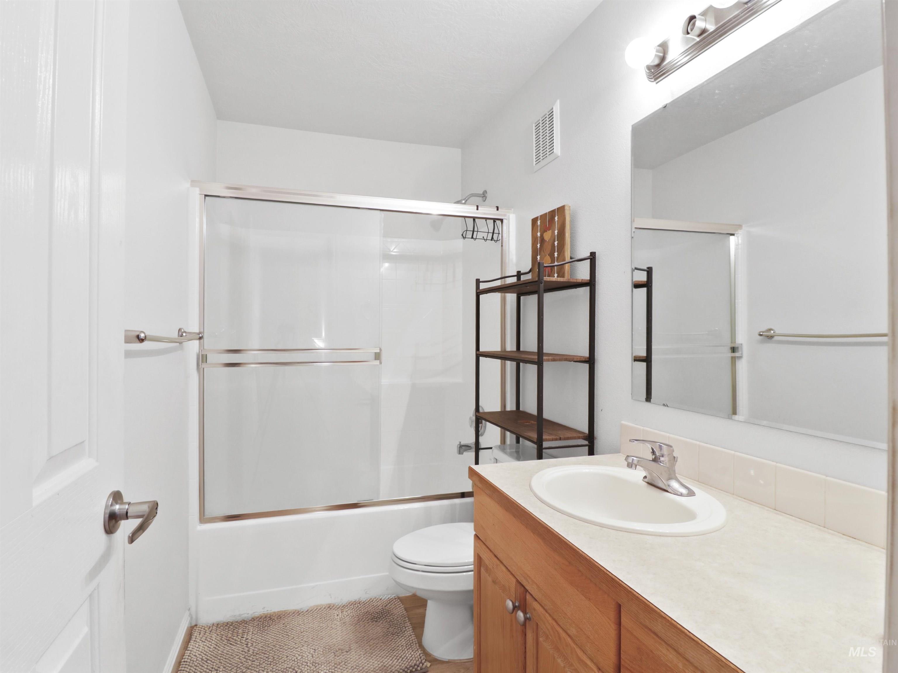 Bathroom with vanity and bath / shower combo with glass door