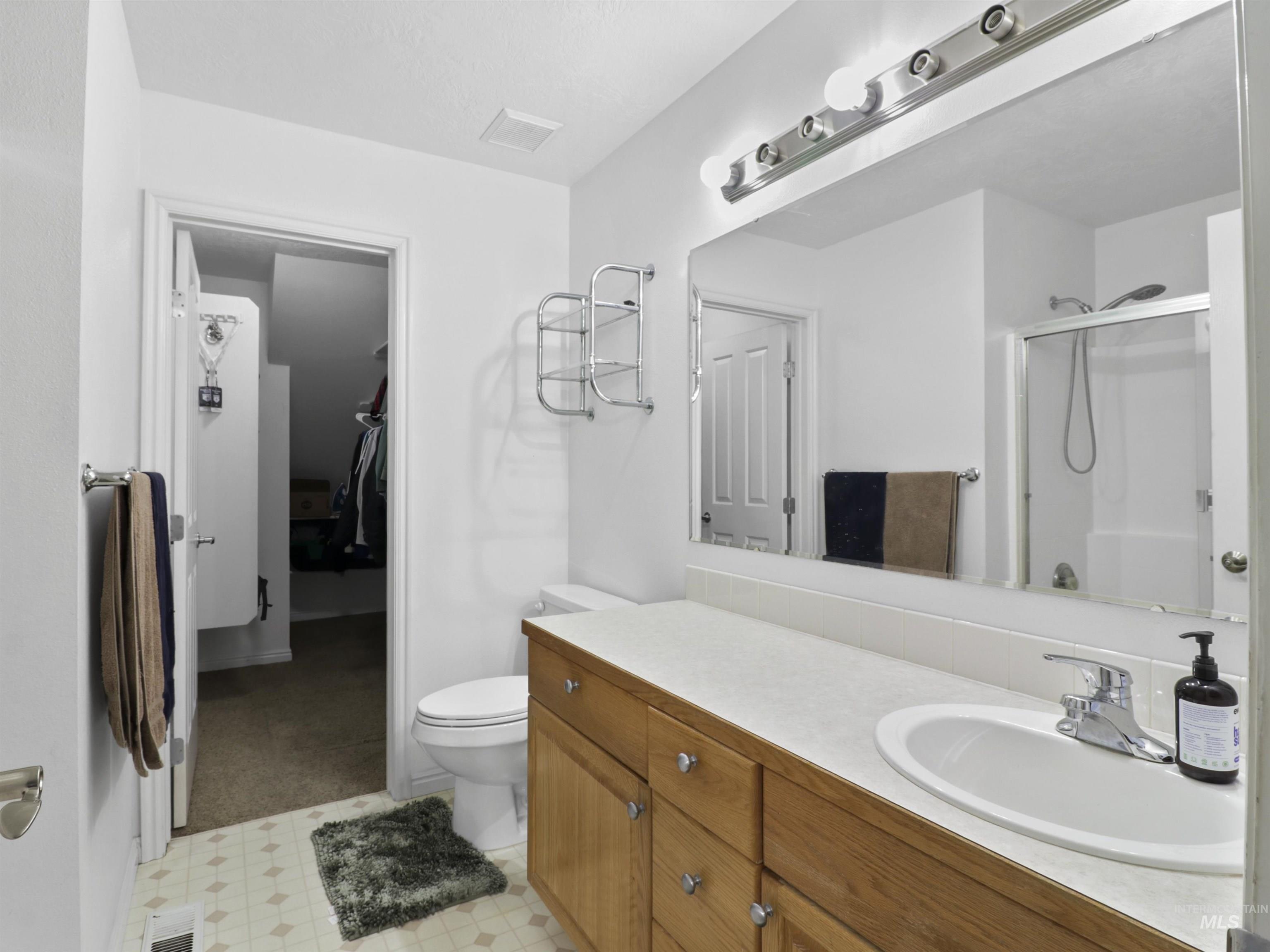 Full bath with vanity, a stall shower, and light flooring