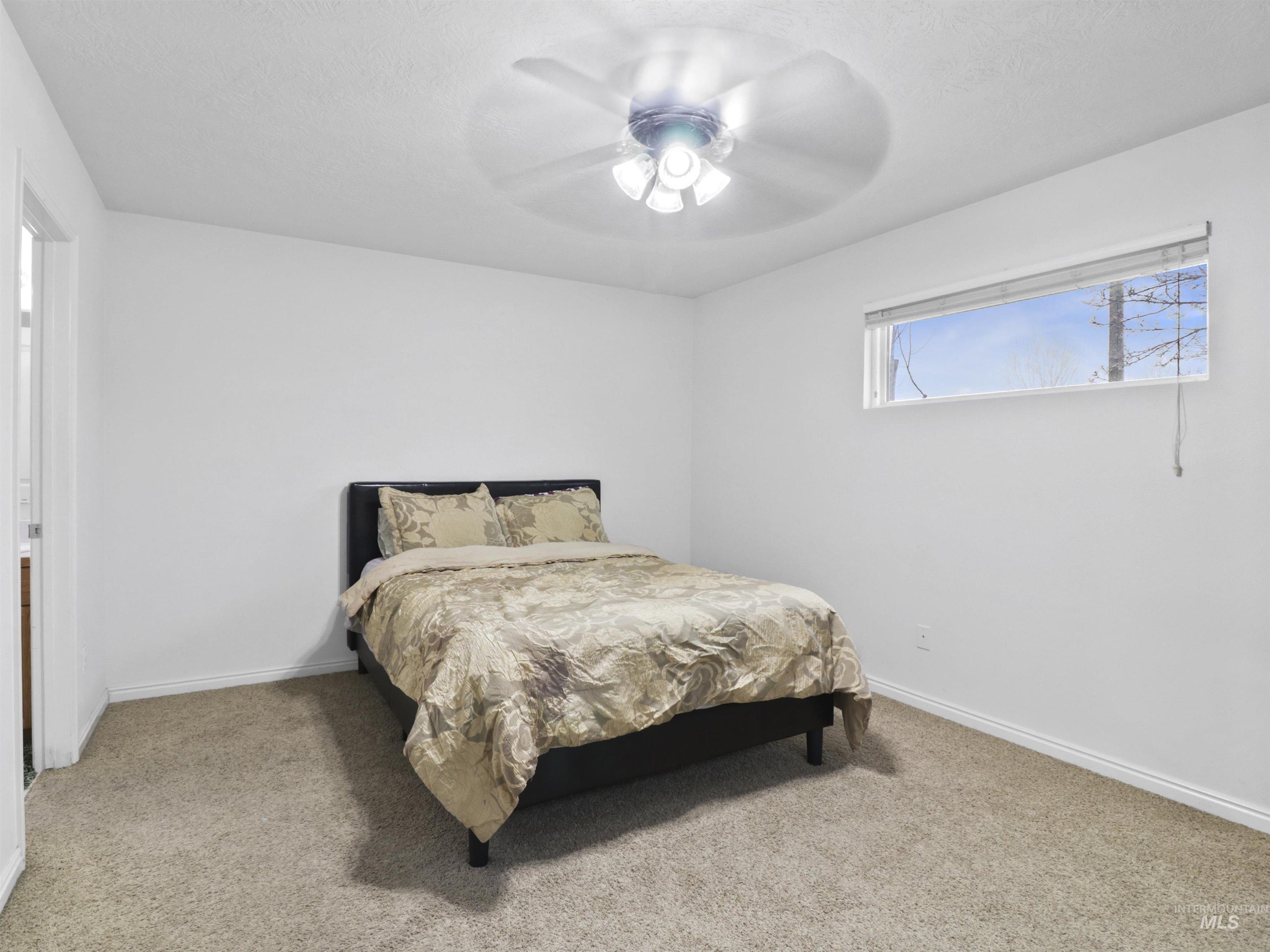 Carpeted bedroom featuring a textured ceiling and ceiling fan