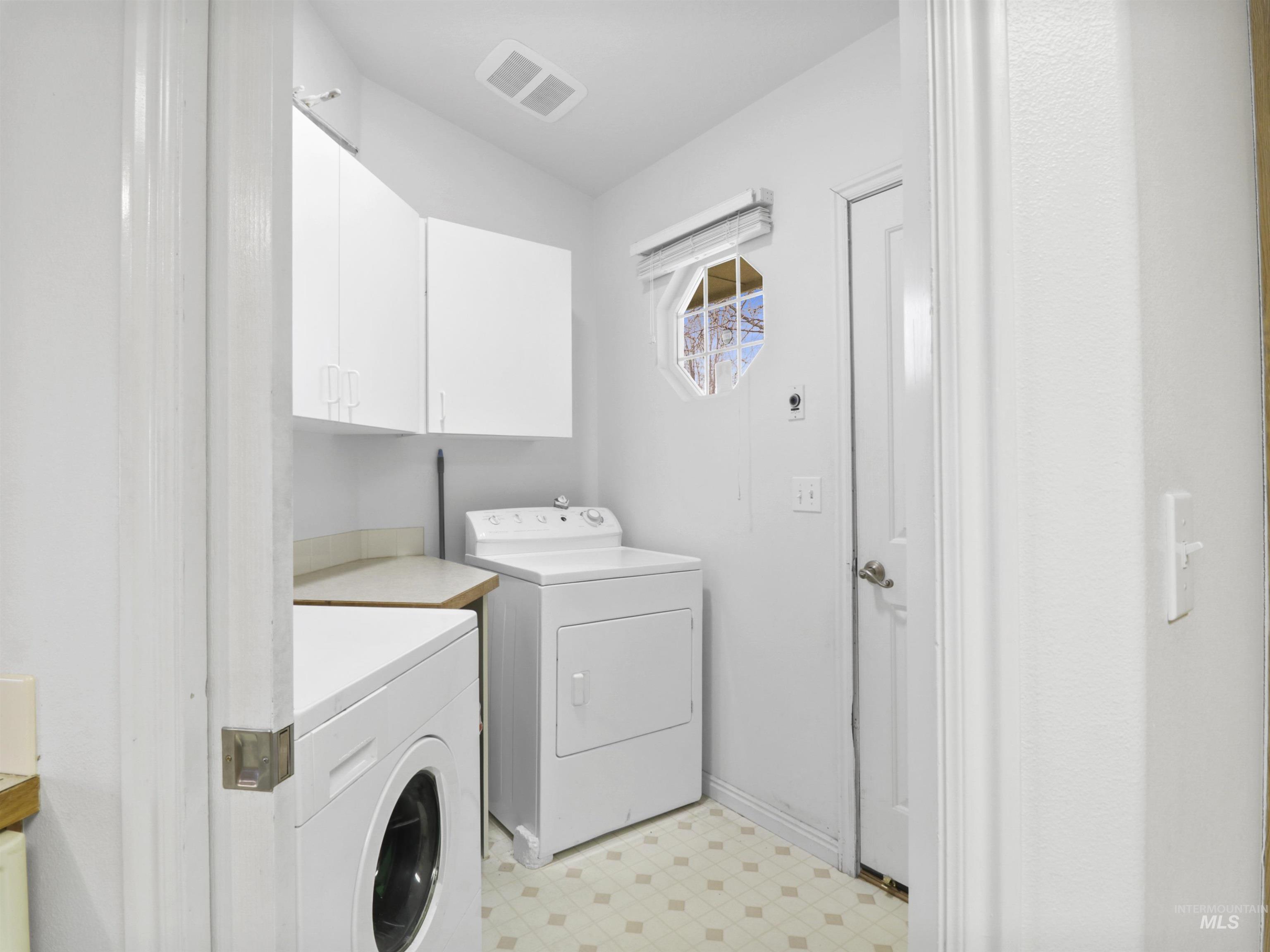 Laundry area featuring light floors, cabinet space, and washing machine and clothes dryer