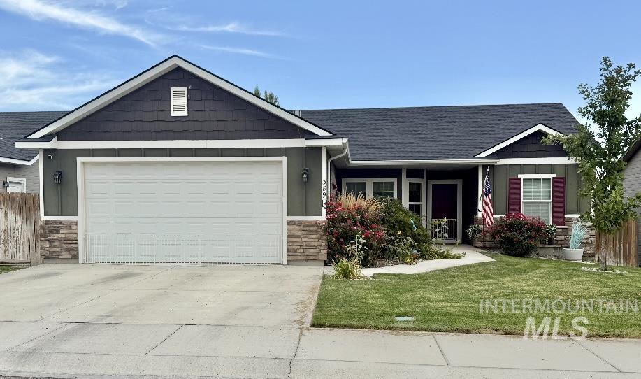 Craftsman inspired home with stone siding, a front yard, driveway, roof with shingles, and an attached garage