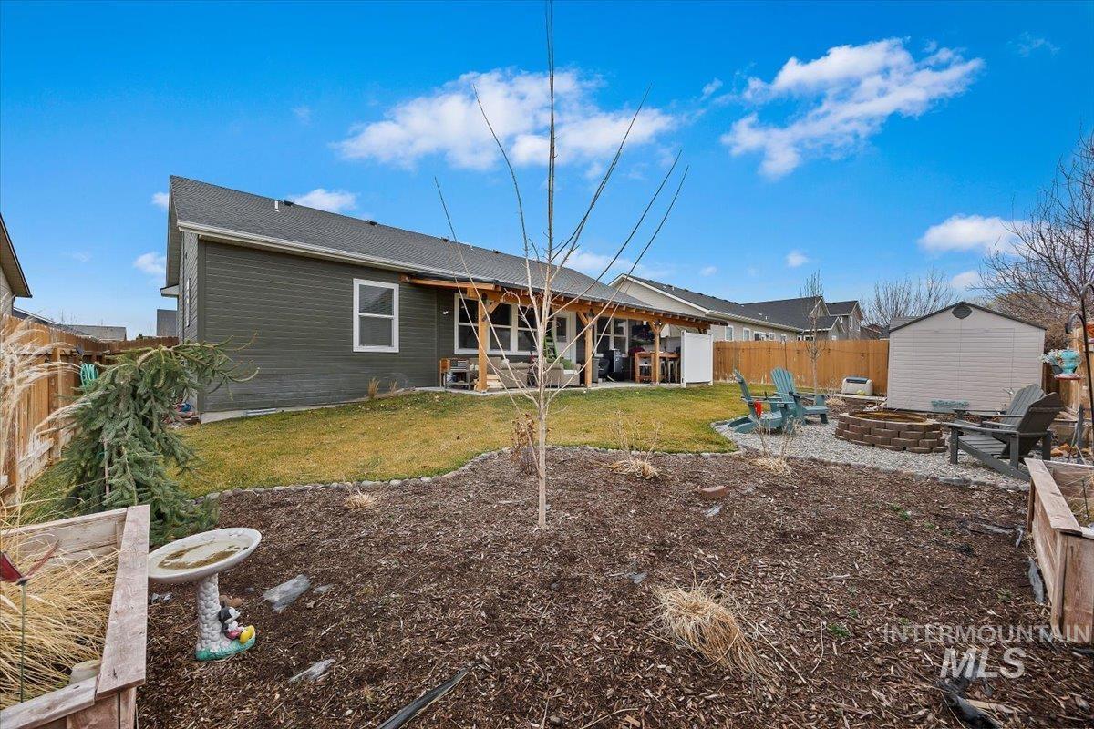 Rear view of house featuring a patio area, a fire pit, a storage unit, and a fenced backyard