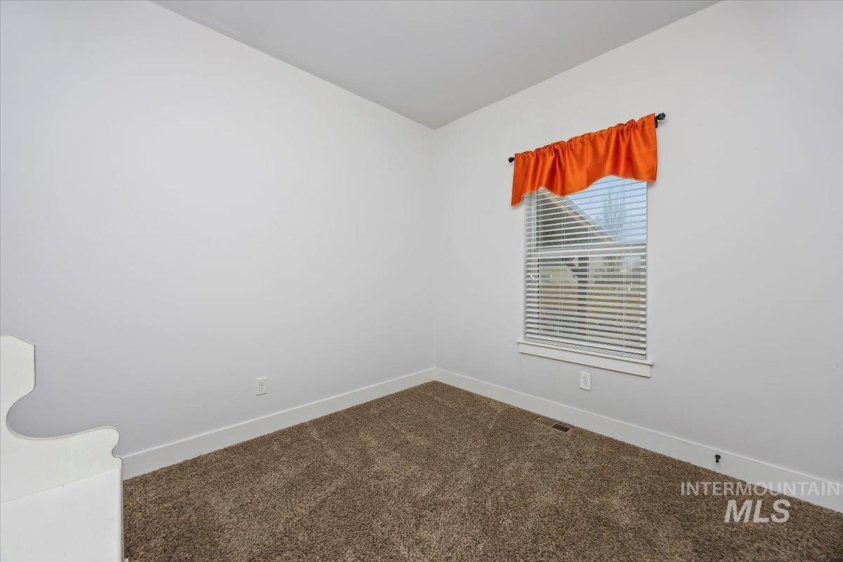 Spare room with dark carpet and lofted ceiling
