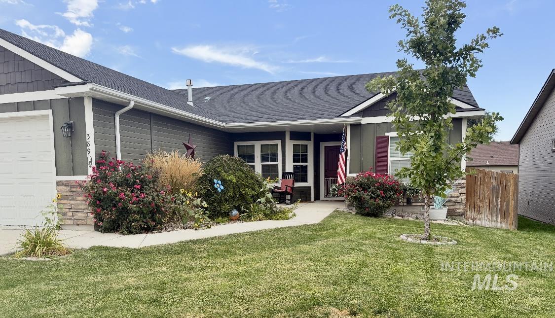 View of front of home featuring roof with shingles, a front yard, board and batten siding, and an attached garage