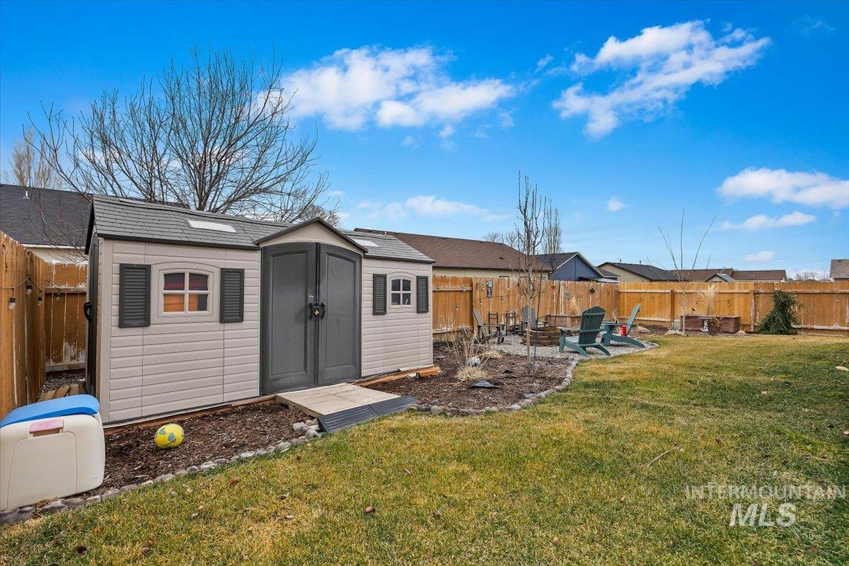 Fenced backyard featuring a fire pit, a shed, and a patio