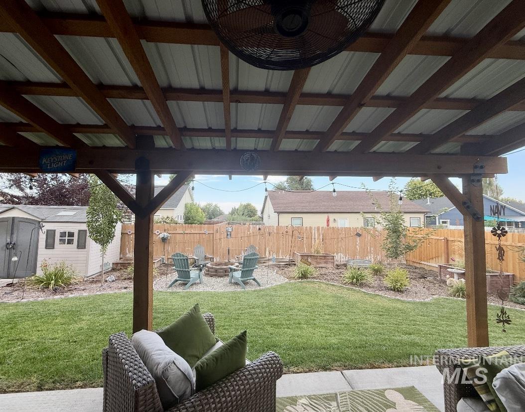 Fenced backyard featuring a patio area, a storage unit, and an outdoor living space with a fire pit