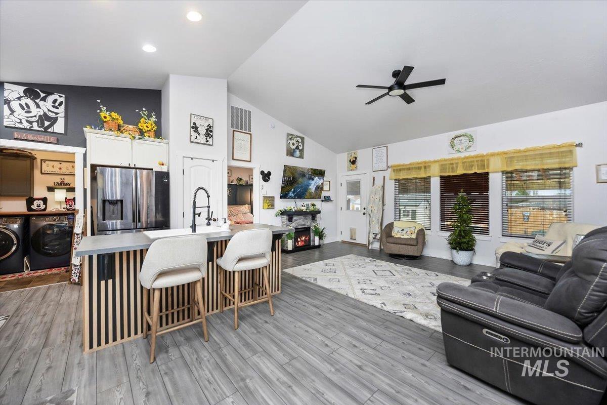 Living room featuring light wood-type flooring, ceiling fan, lofted ceiling, and separate washer and dryer