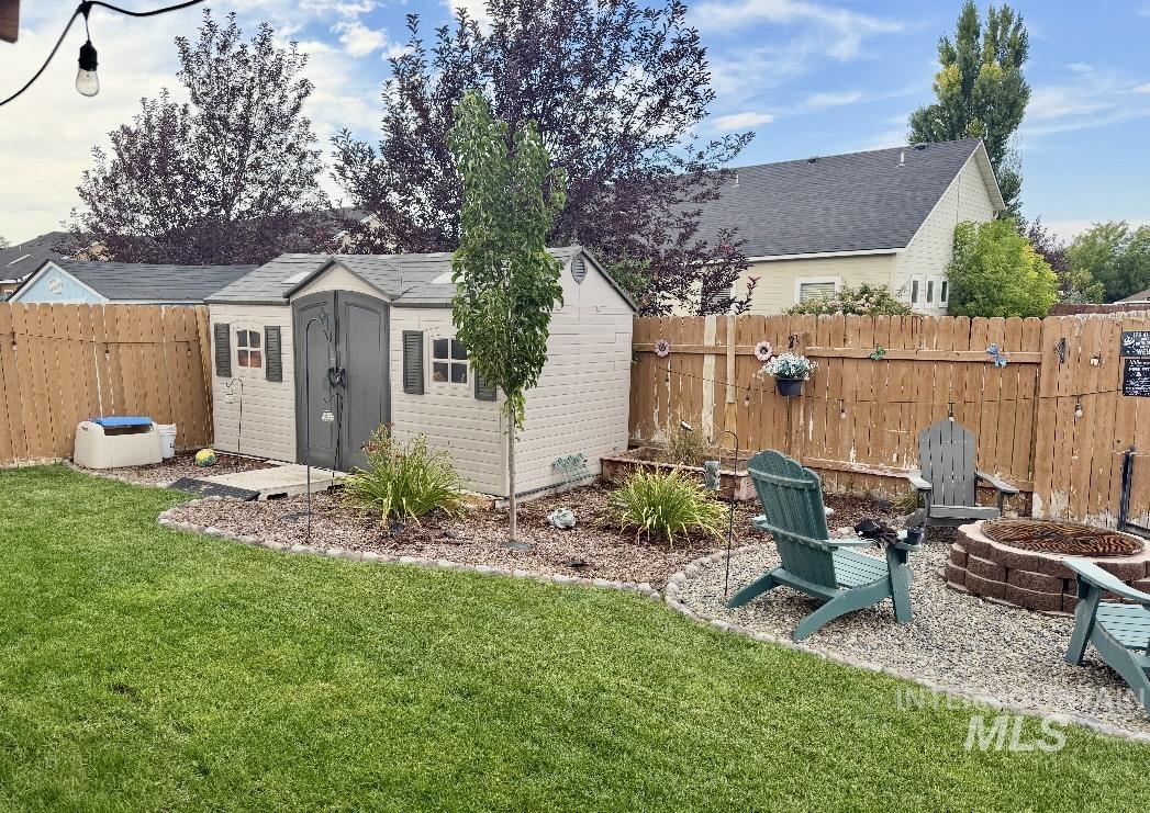Fenced backyard featuring a fire pit and a storage shed