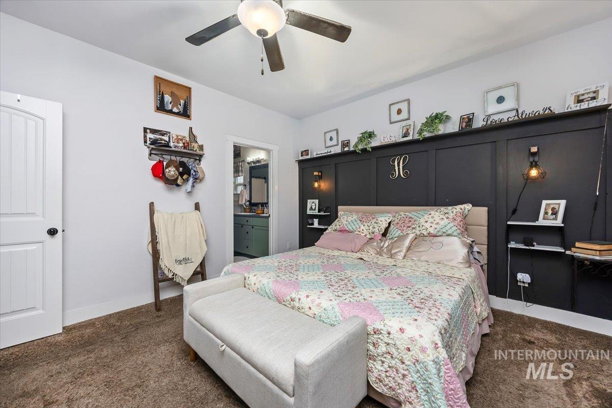 Bedroom featuring dark colored carpet, a ceiling fan, and ensuite bath