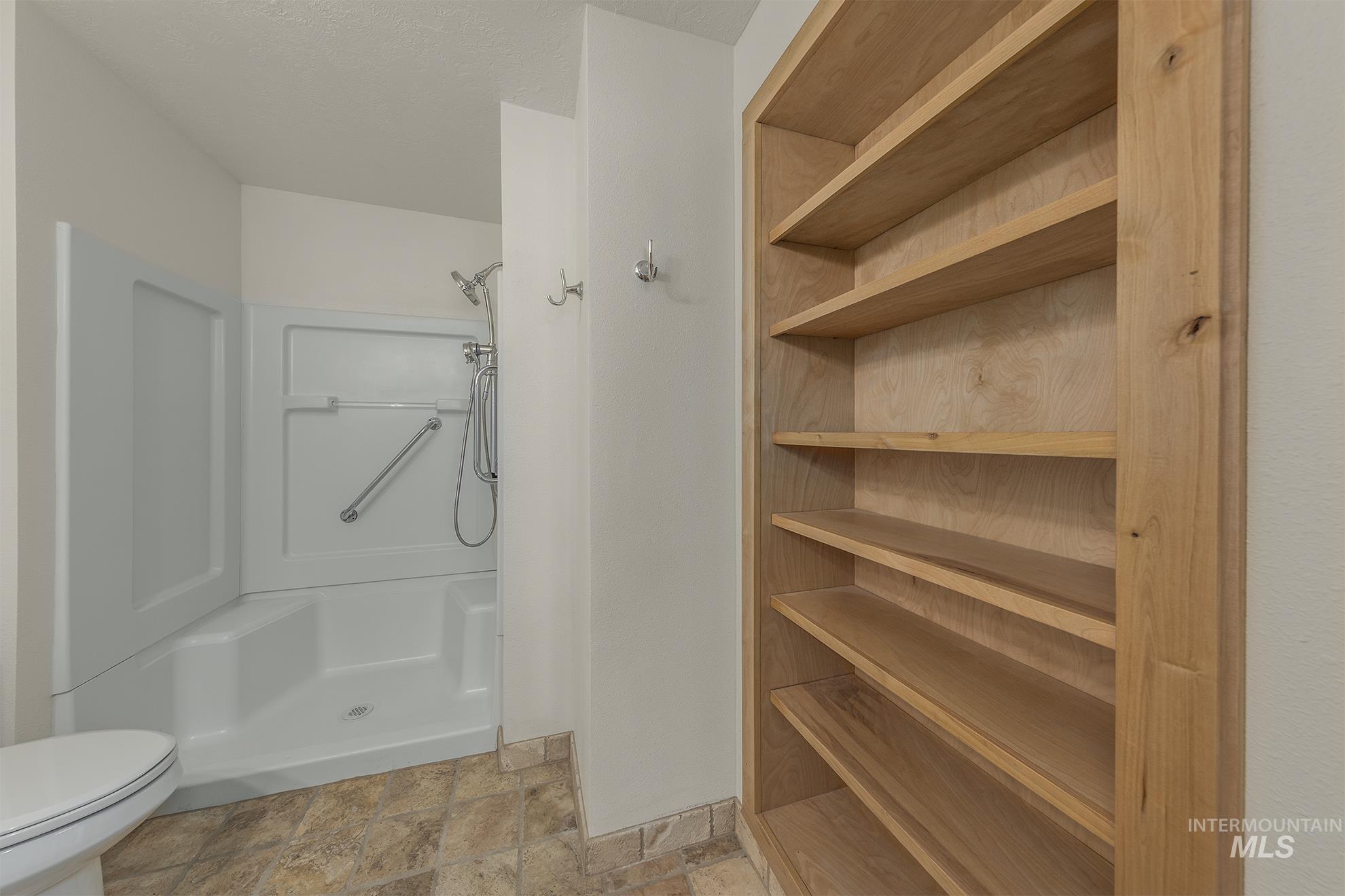 Full bath featuring a stall shower and light stone finish flooring