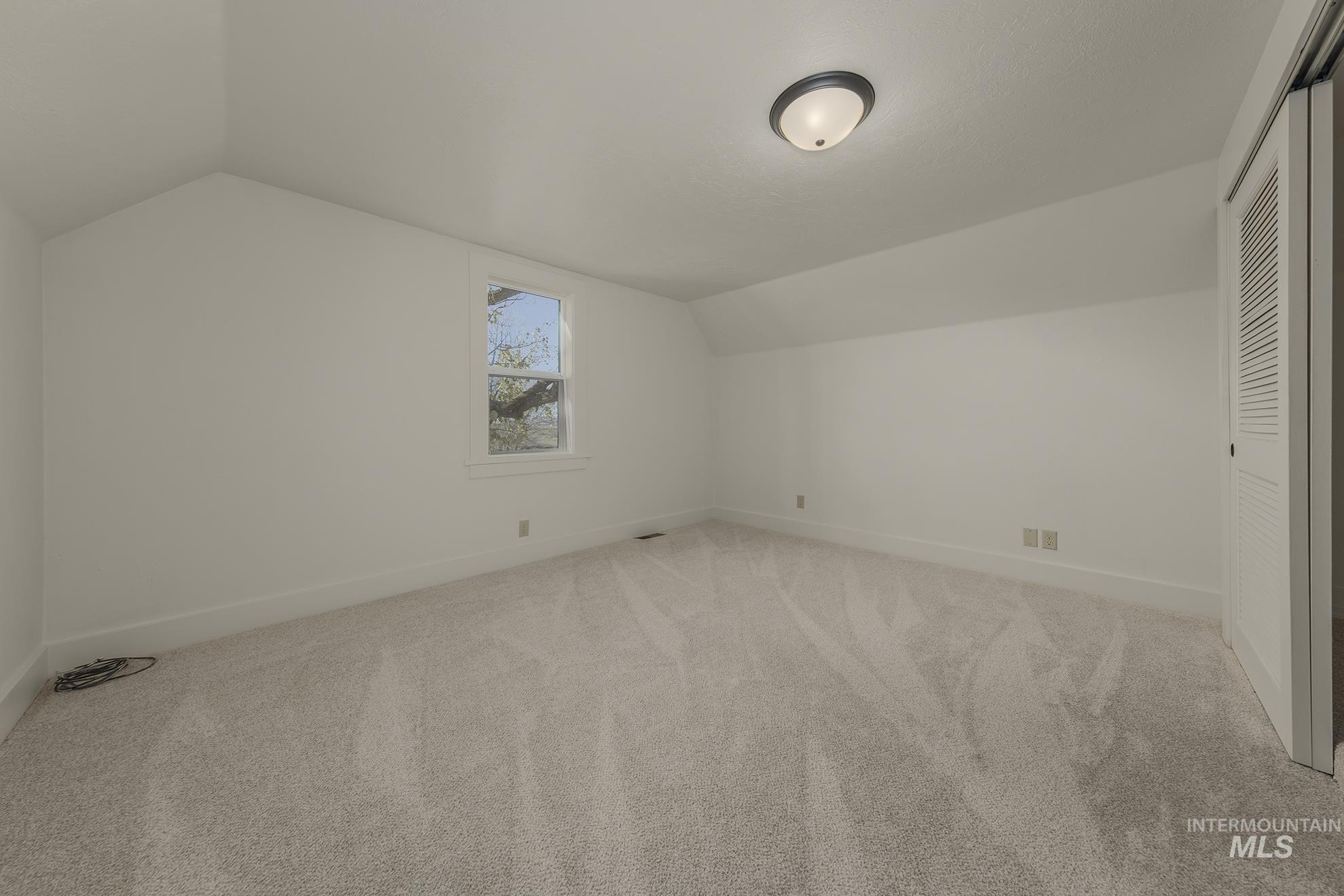 Additional living space with lofted ceiling and carpet floors