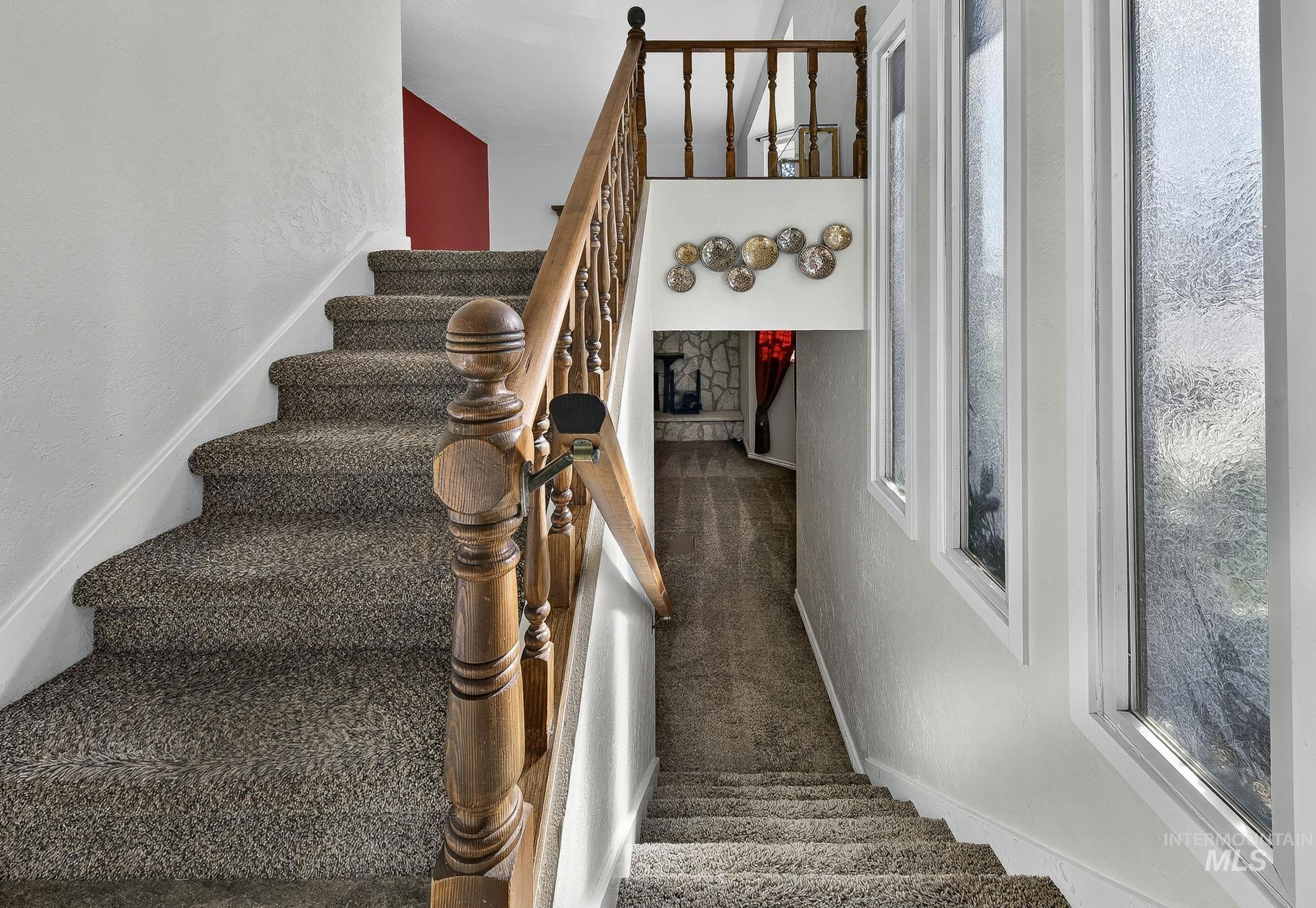 Stairway featuring a textured wall and carpet flooring