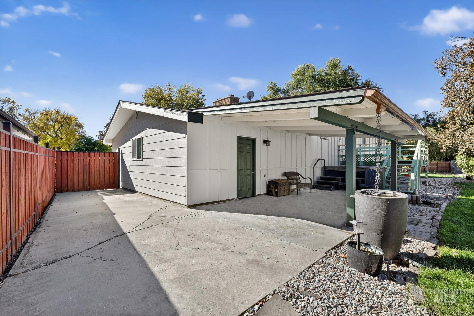 Rear view of property featuring a fenced backyard, a patio, a hot tub, and a chimney
