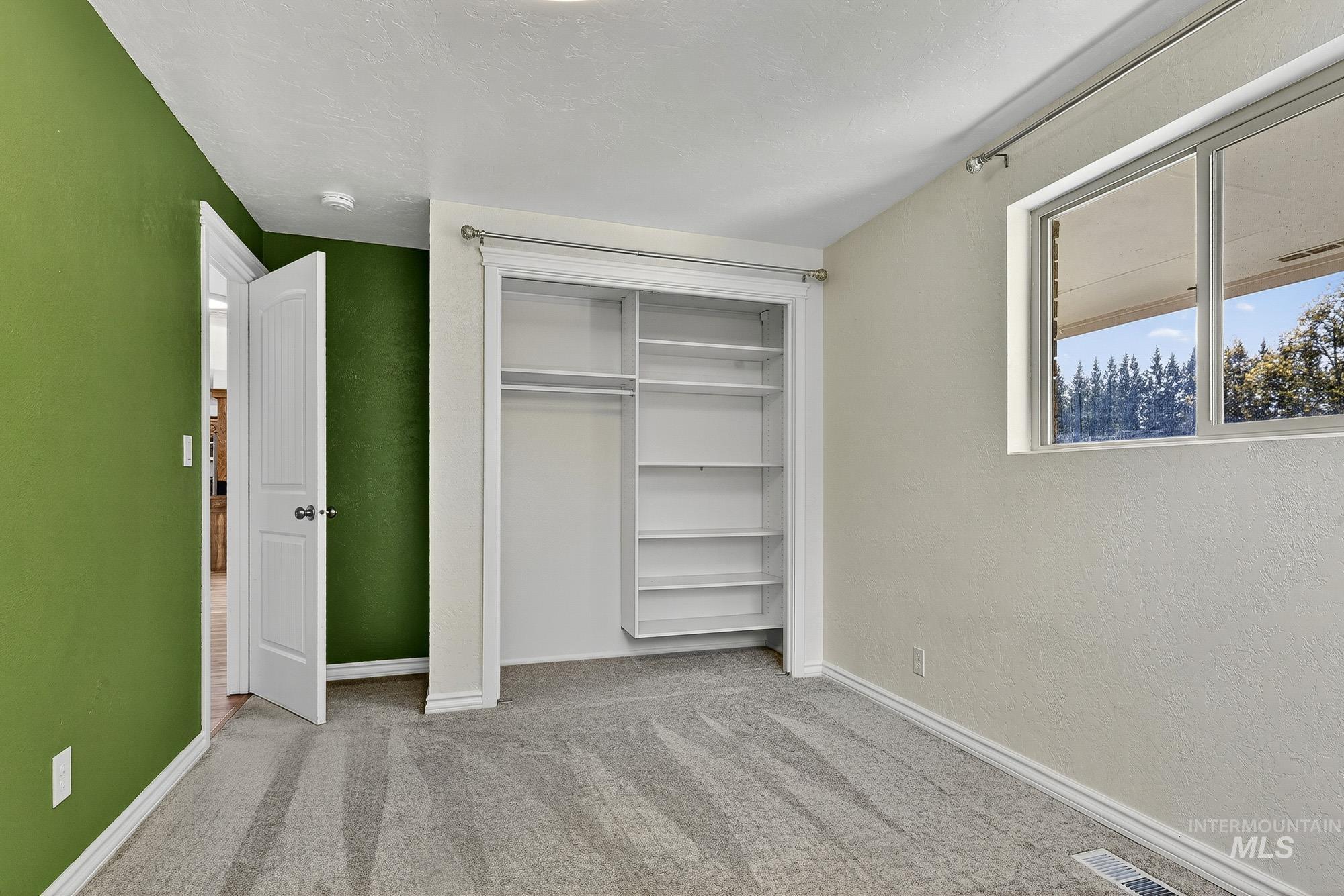 Unfurnished bedroom with carpet, a textured wall, and a closet