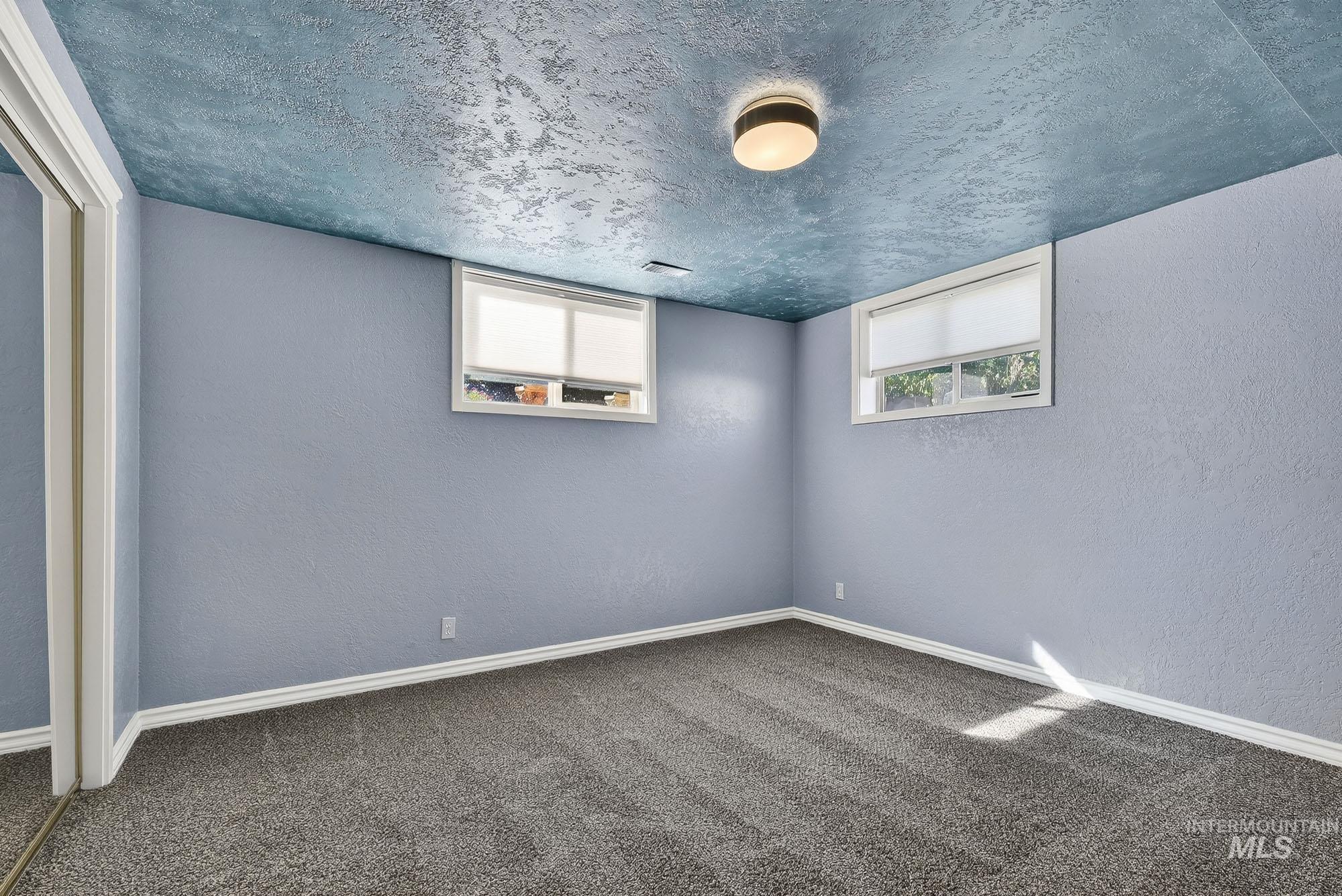 Basement featuring a textured wall, carpet flooring, healthy amount of natural light, and a textured ceiling