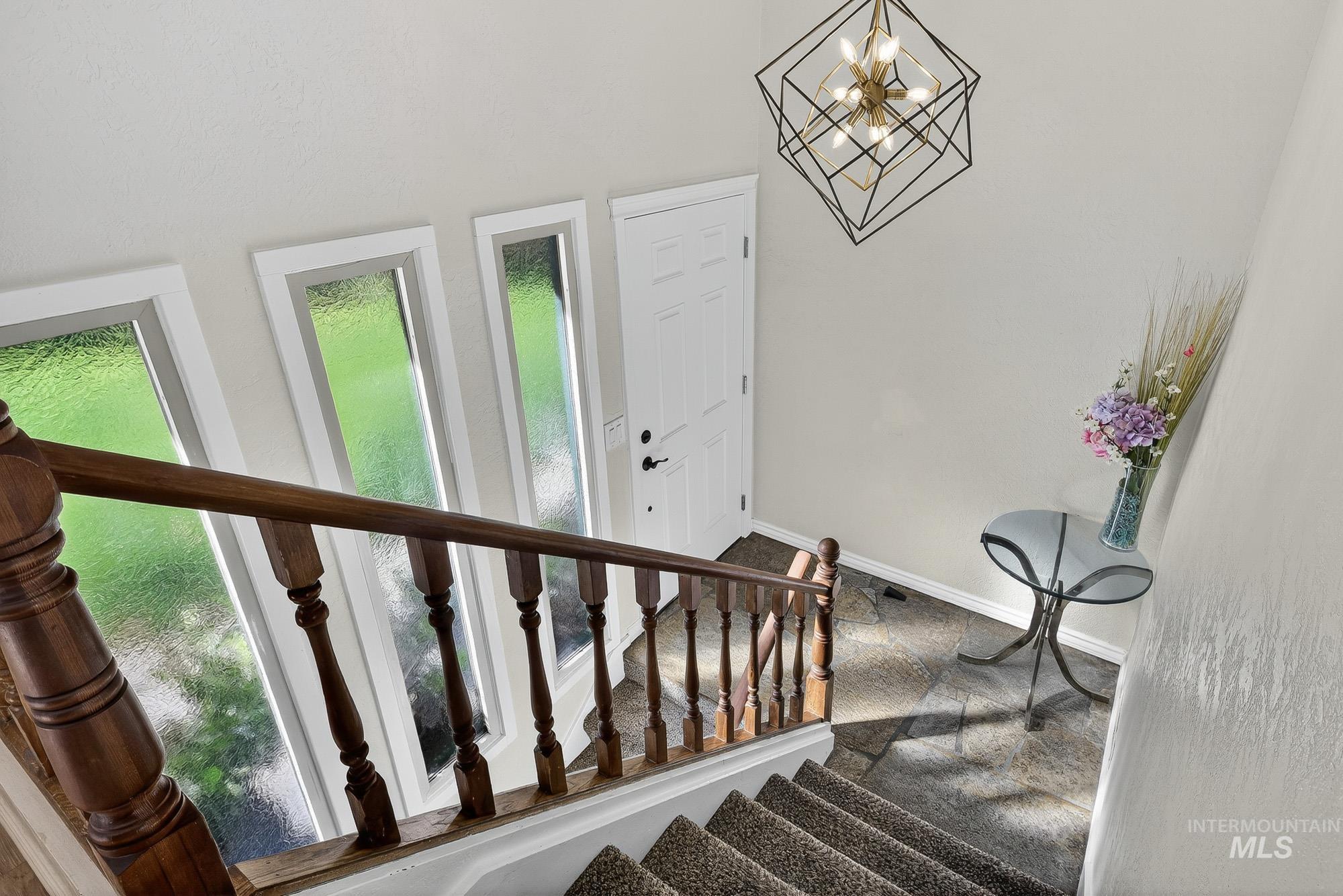 Stairway with baseboards and a chandelier