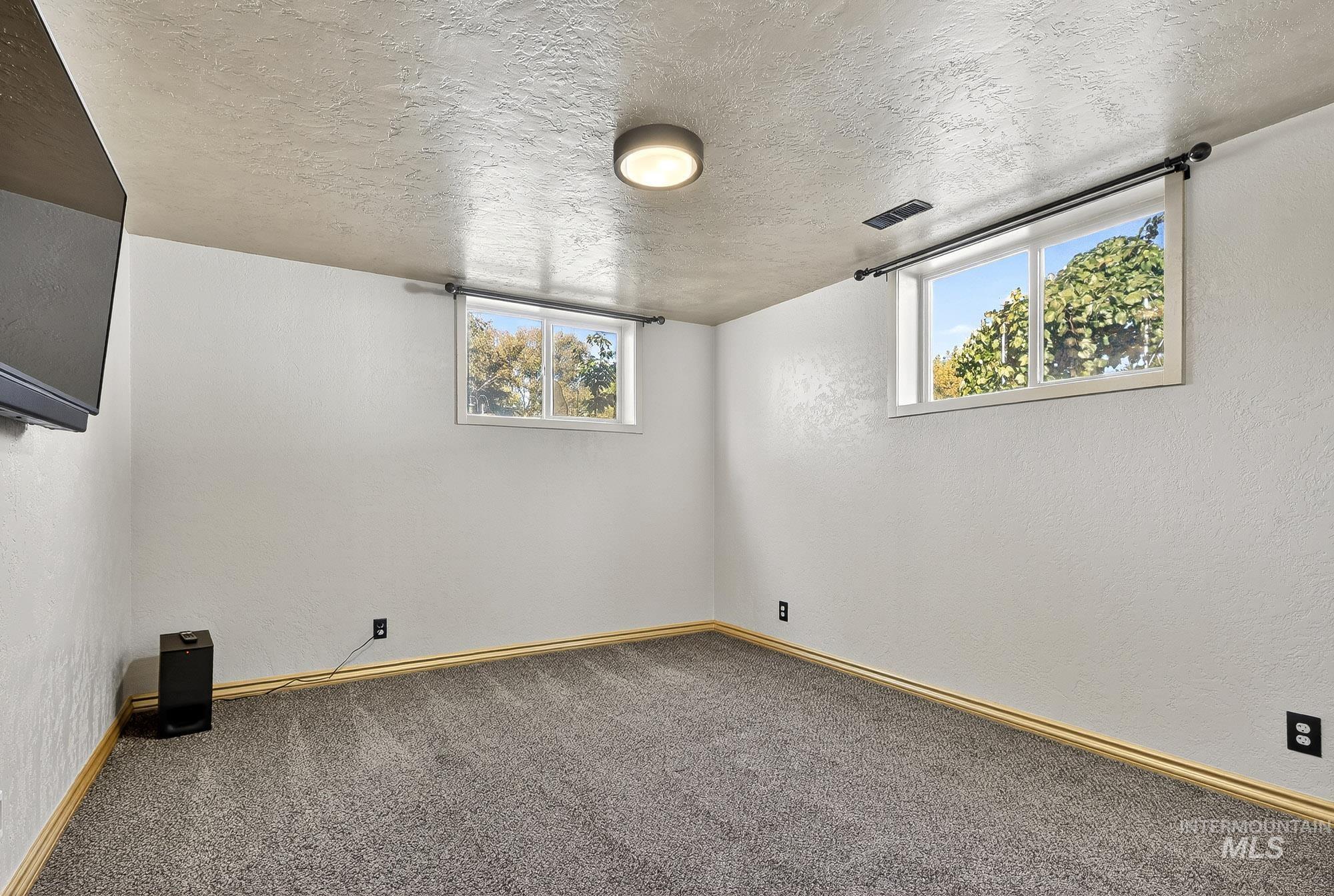 Below grade area featuring a textured ceiling, a textured wall, and carpet flooring