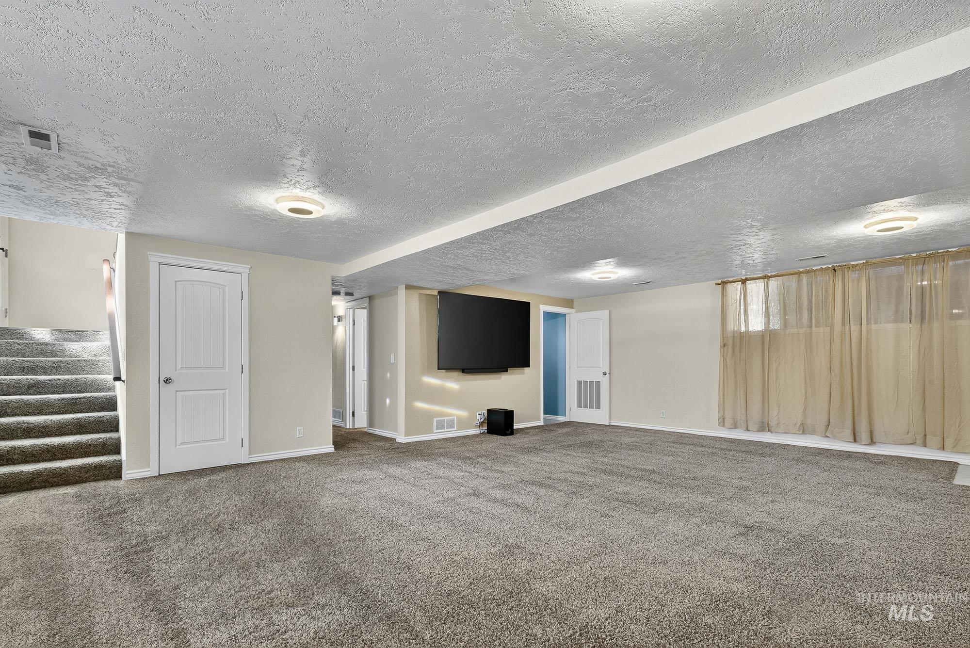 Finished basement with stairway, carpet floors, and a textured ceiling. TV is included!