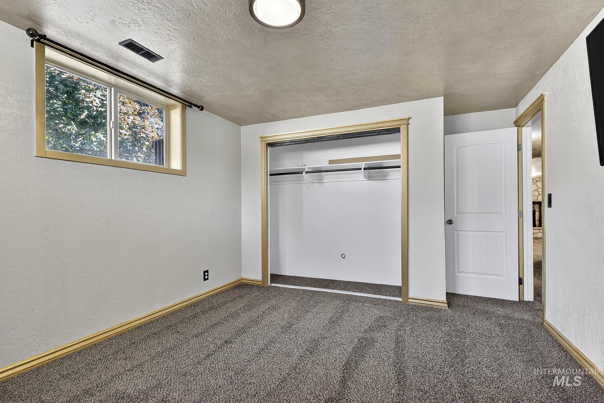 Unfurnished bedroom featuring carpet, a textured ceiling, a closet, and a textured wall