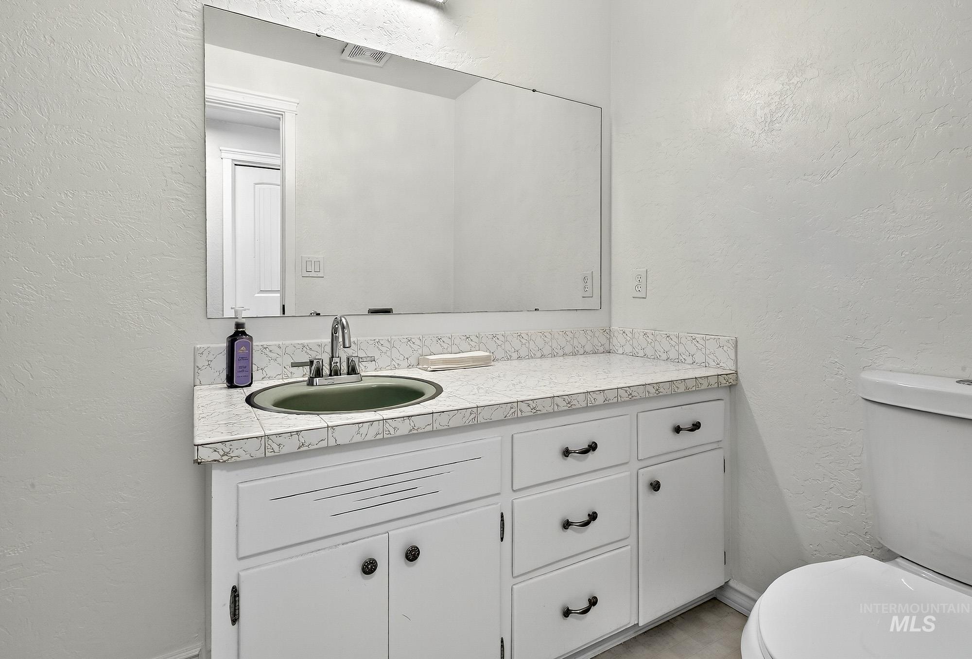 Bathroom featuring a textured wall and vanity