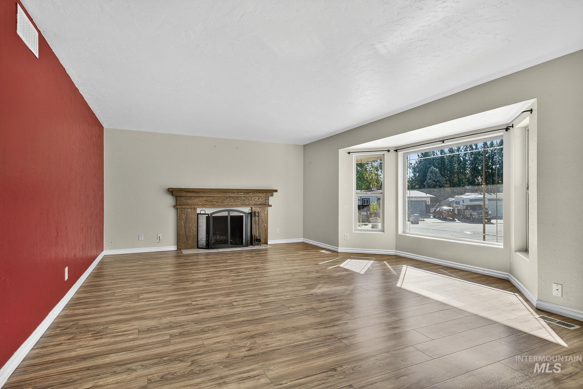 Unfurnished living room with a fireplace, wood finished floors, and a textured ceiling