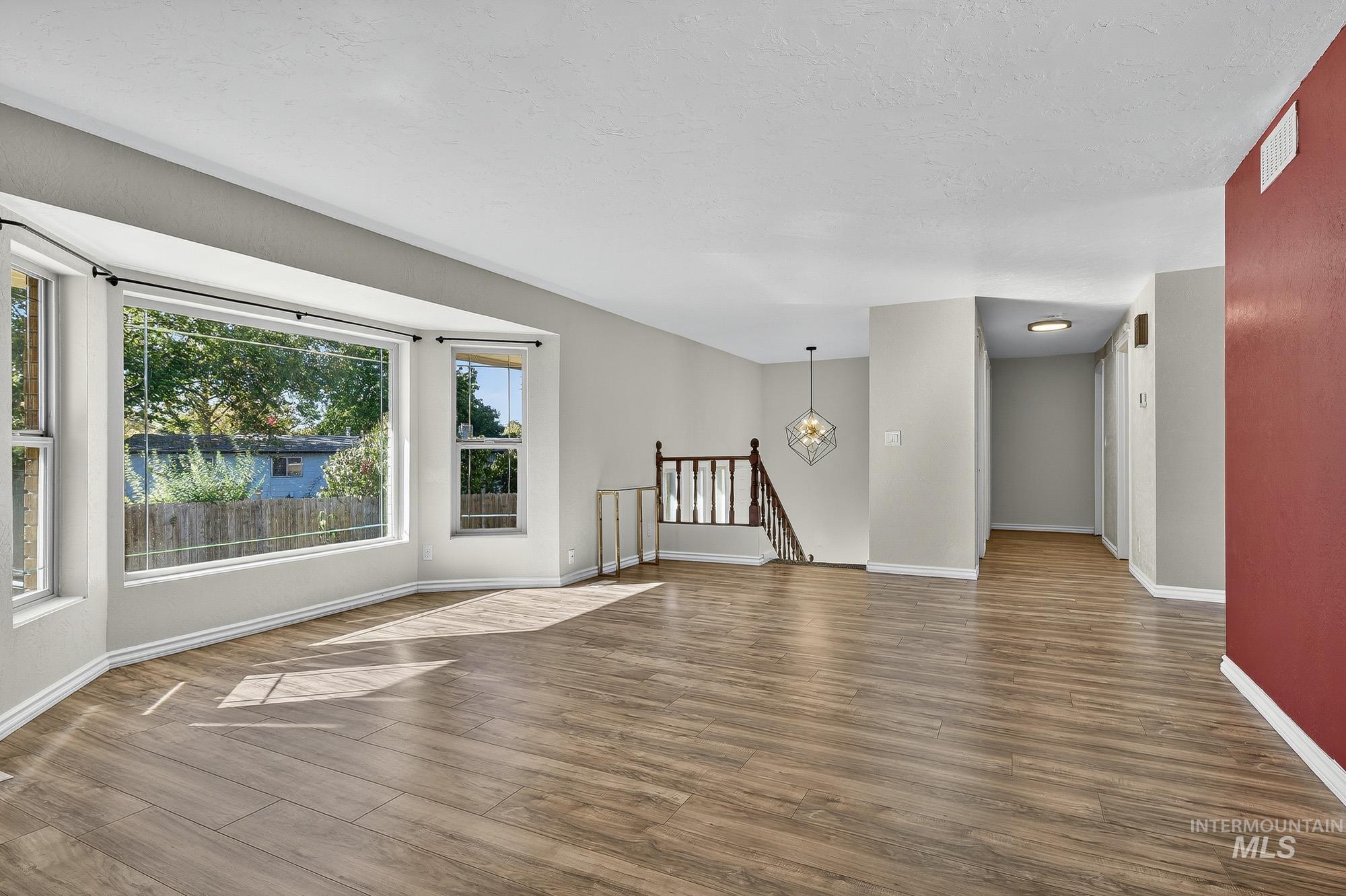 Unfurnished living room featuring wood finished floors and baseboards