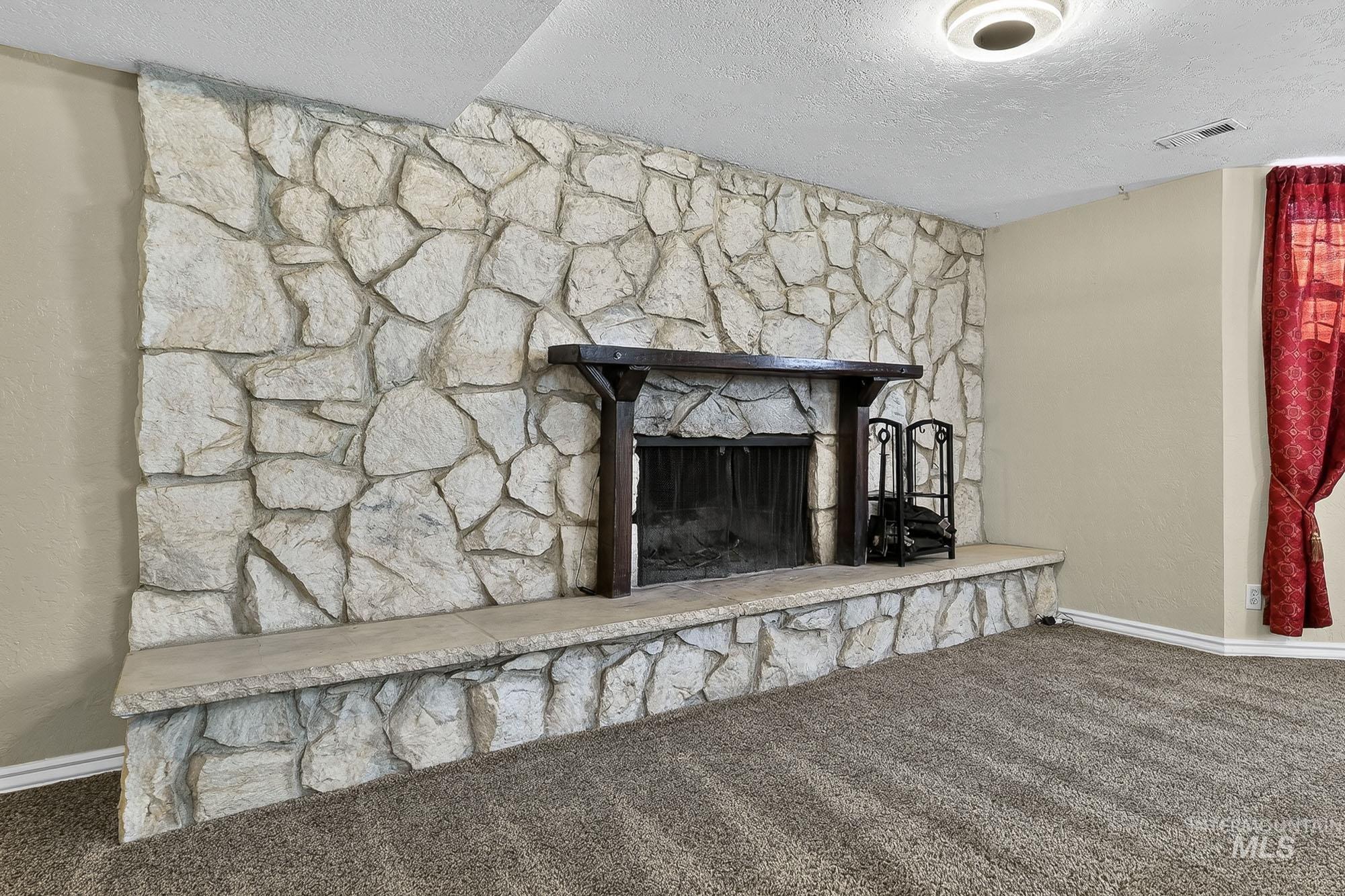 Detailed view of a textured ceiling, carpet, and a fireplace