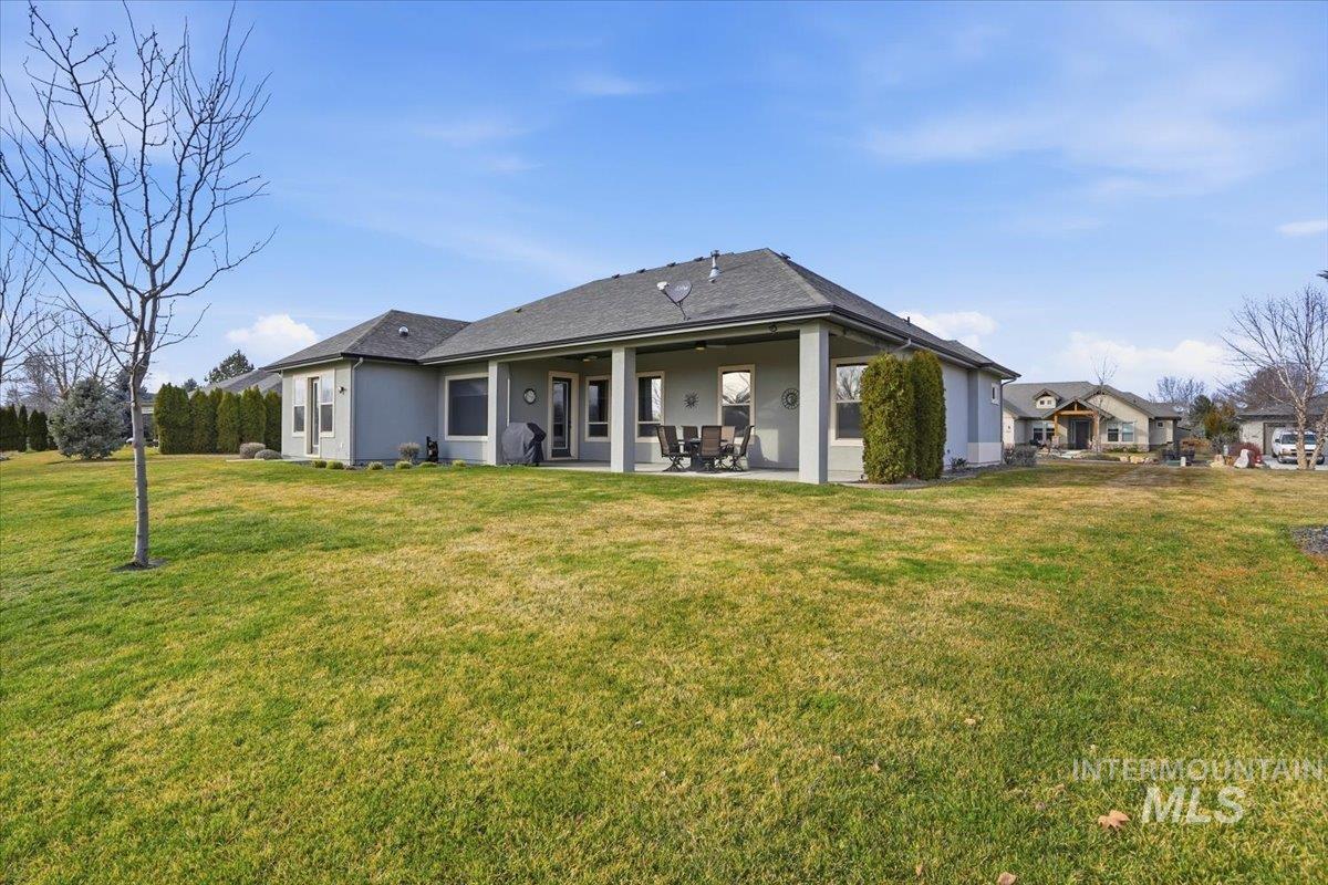 Rear view of house featuring stucco siding, a patio area, and a yard