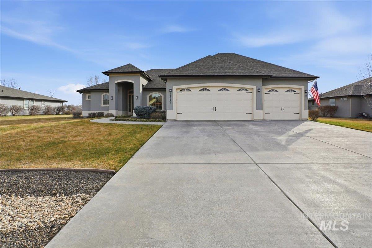 View of front of house with a front lawn, concrete driveway, stucco siding, a garage, and a shingled roof