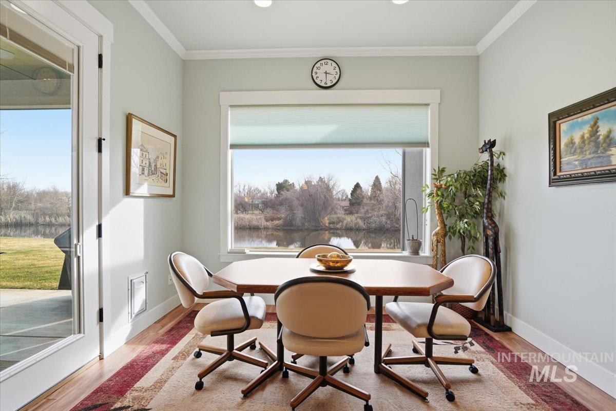 Dining area featuring crown molding, wood finished floors, and a water view