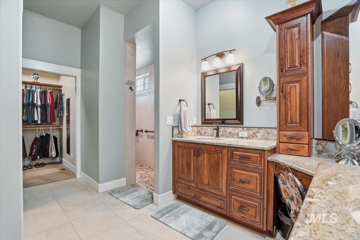 Bathroom featuring vanity, a spacious closet, walk in shower, and light tile patterned flooring